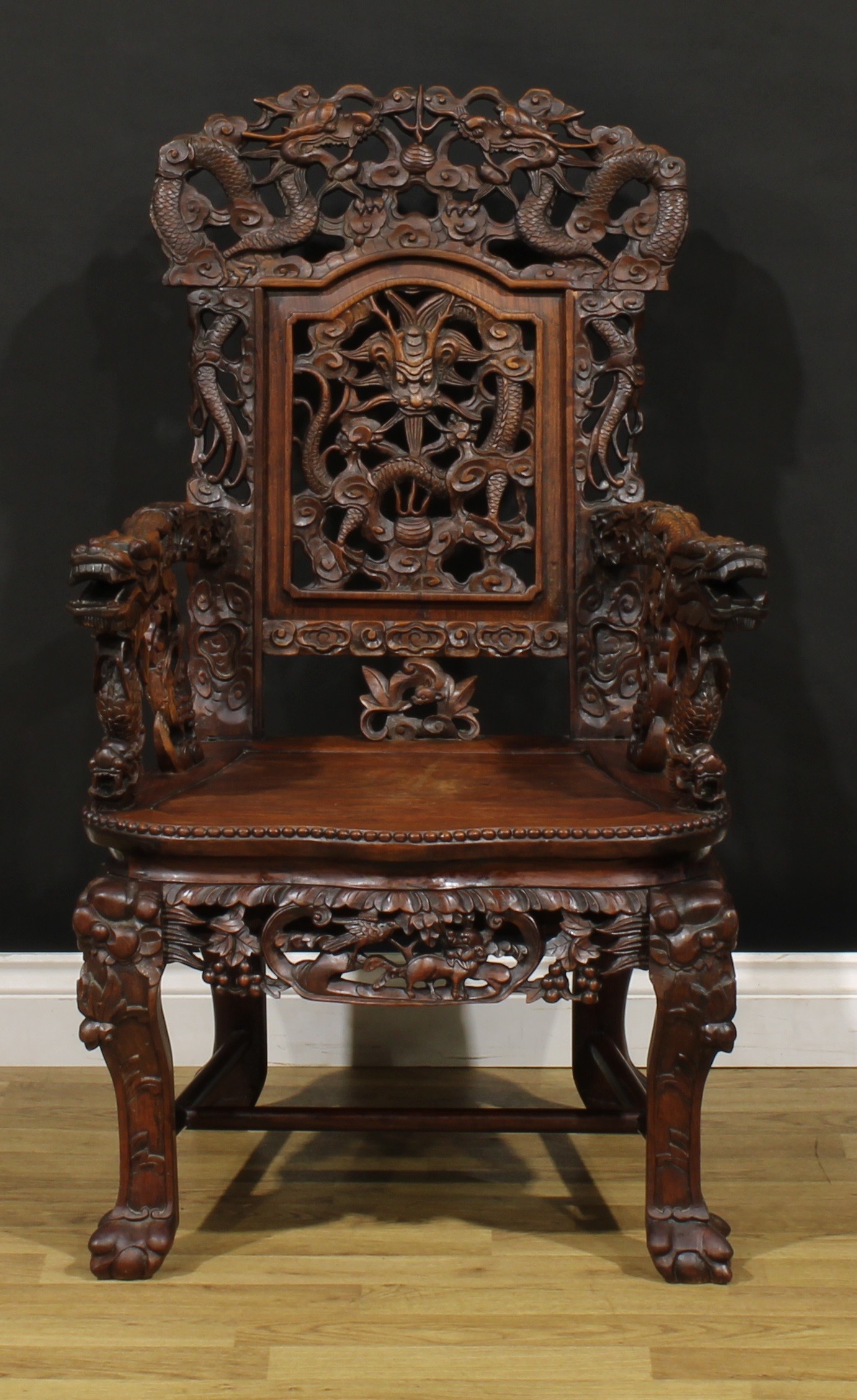A Chinese hardwood armchair, carved throughout with dragons and stylised clouds, serpentine seat with beaded edge, cabriole forelegs, H-stretcher, ball and claw feet, 105.5cm high, 64cm wide, the seat 36cm wide and 35cm deep