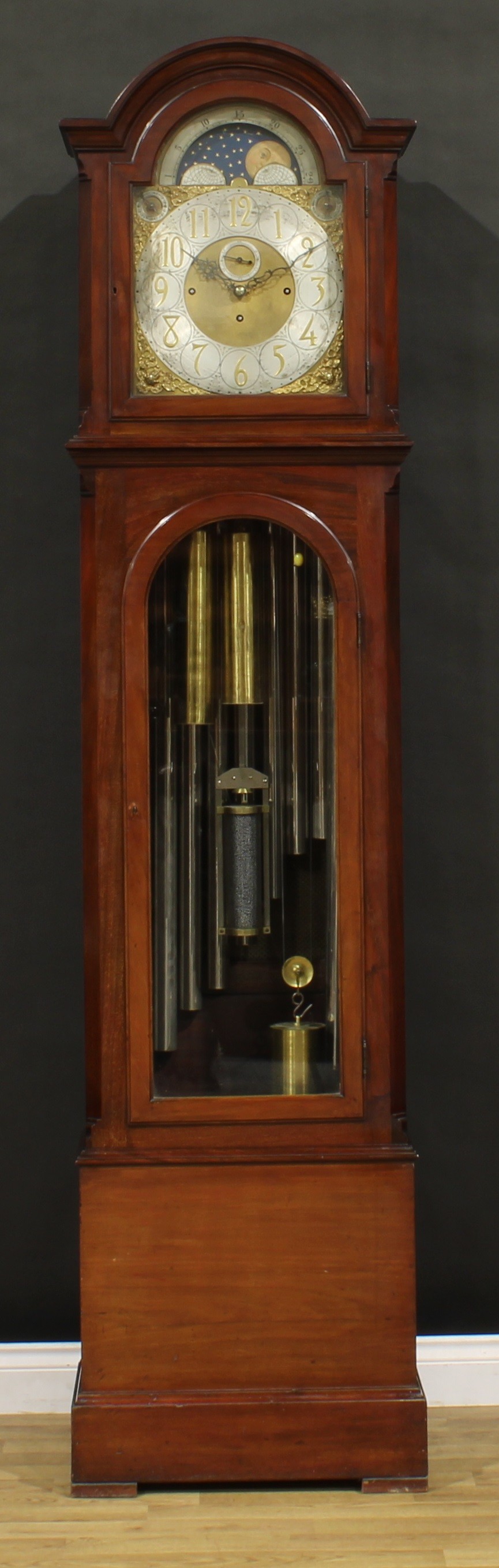 A substantial Edwardian mahogany longcase clock, 33.5cm arched brass dial applied with Arabic numerals, subsidiary seconds dial, rolling moon to arch, Chime/Silent and Whittington chimes/Westminster chimes selectors to upper angles, triple winding holes, eight day movement striking on nine Harringtons’ patent tubular bells, the case with arched glazed door to waist, 227.5cm high, 56cm wide, 32.5cm deep, c.1905