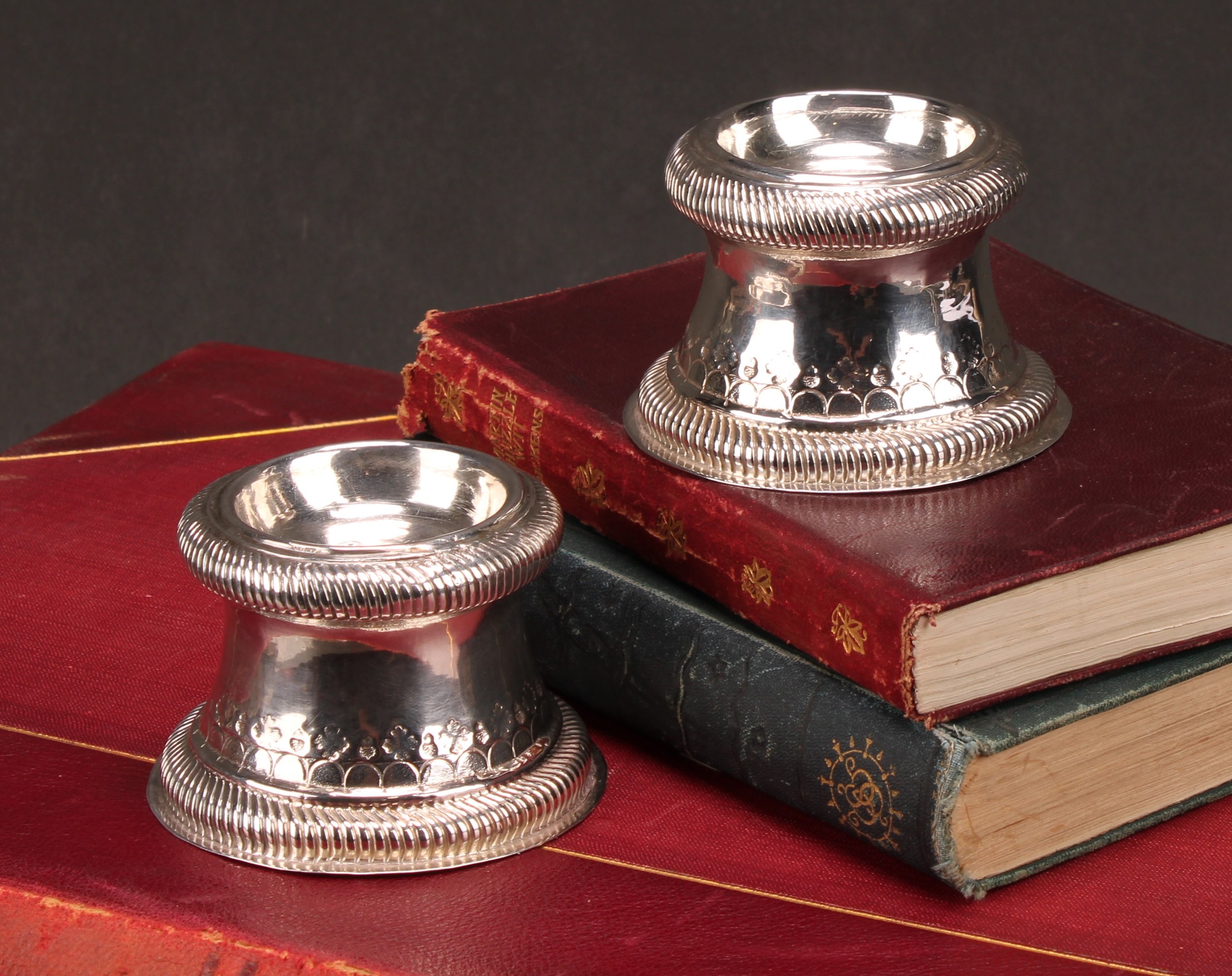 A pair of William III Britannia silver waisted cylindrical trencher salts, gadrooned borders, chased and punched with bands of lunettes and leafy bosses, 7.5cm diam, William Keatt, London 1697