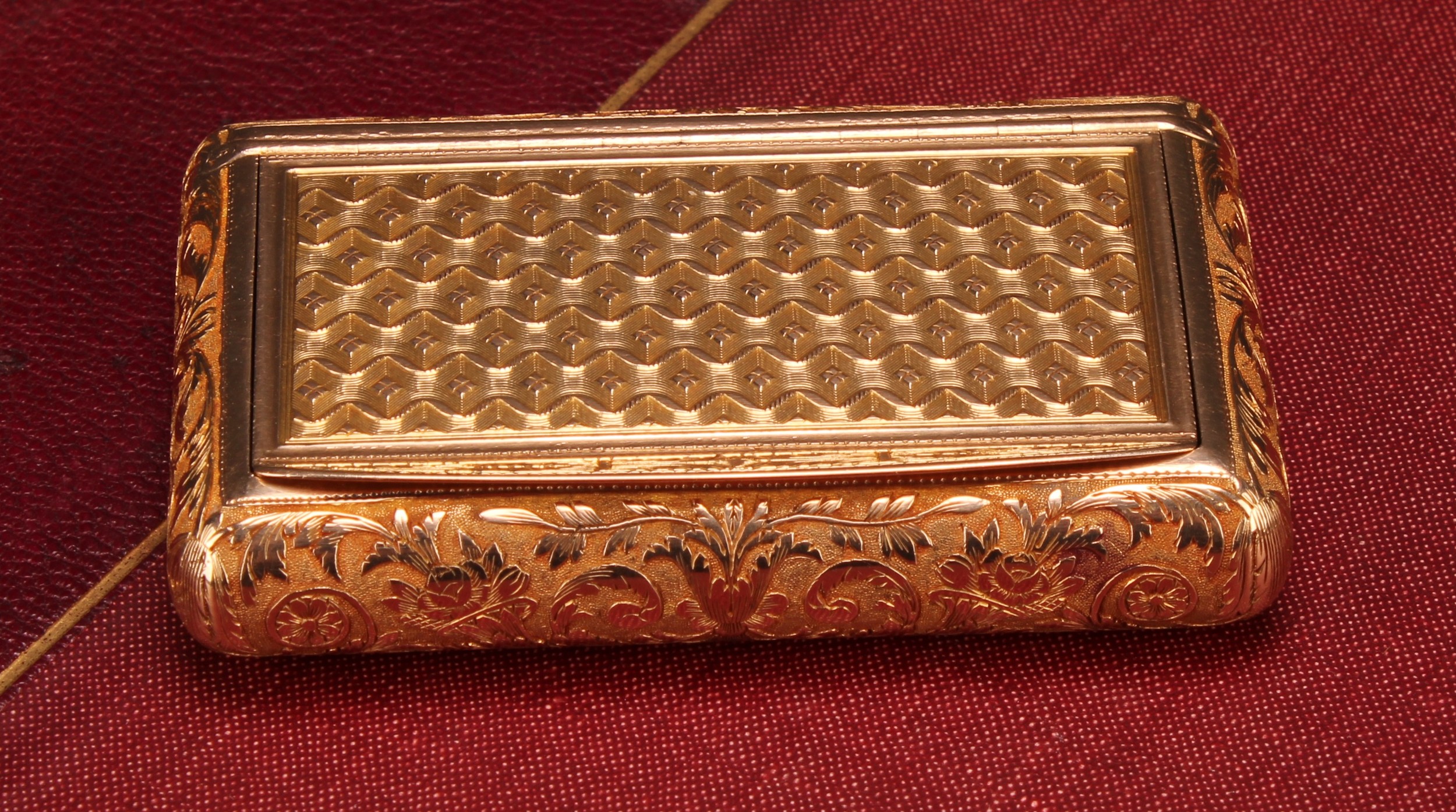A 19th century French gold rectangular snuff box, by Louis François Tronquoy (fl. 1827-71), the press closing cover decorated with an engine turned ground with a protruding foliate thumbpiece, above waisted sides profusely chased with foliate scrolls, maker's mark to cover and central well, Paris, 53.7g