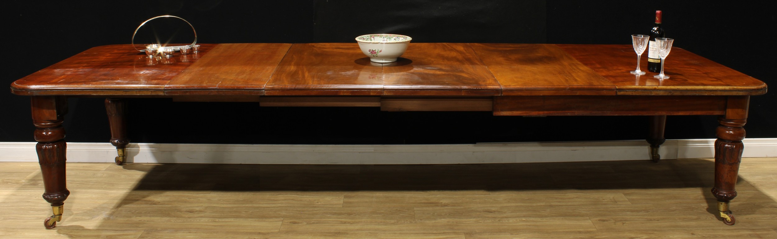 A William IV mahogany extending dining table, rounded rectangular top, four additional leaves, turned legs carved with lotus, ceramic casters, 72cm high, 152.5cm extending to 351cm long, 122cm wide, c.1835