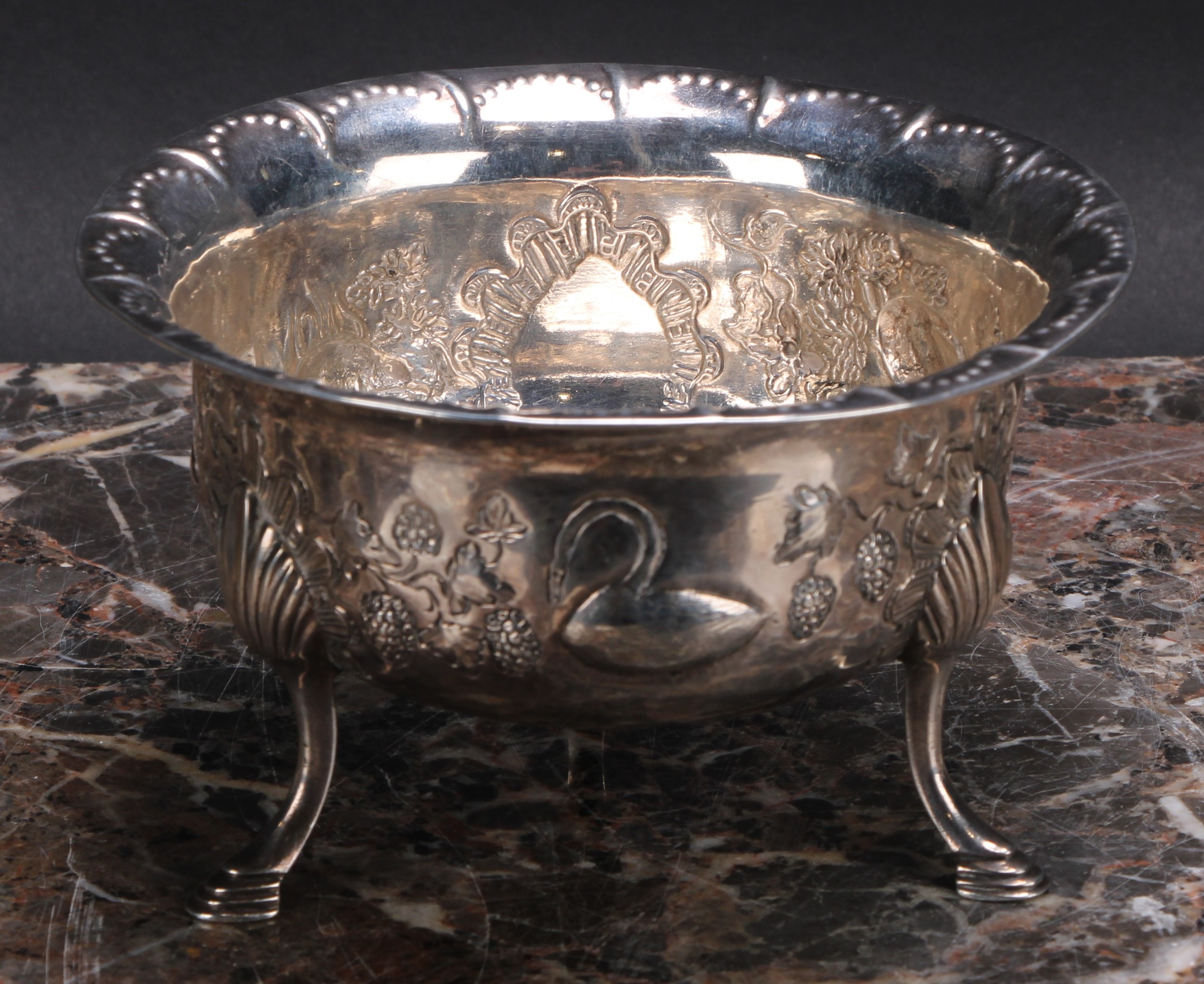 An Irish Provincial silver bowl, chased with a bird, a rabbit, a dog and a swan, in a landscape, amongst fruiting vine, punch-beaded border, hoof feet with shells to knees, 14cm diam, marked PW, and IM overstruck, possibly Limerick, 172g