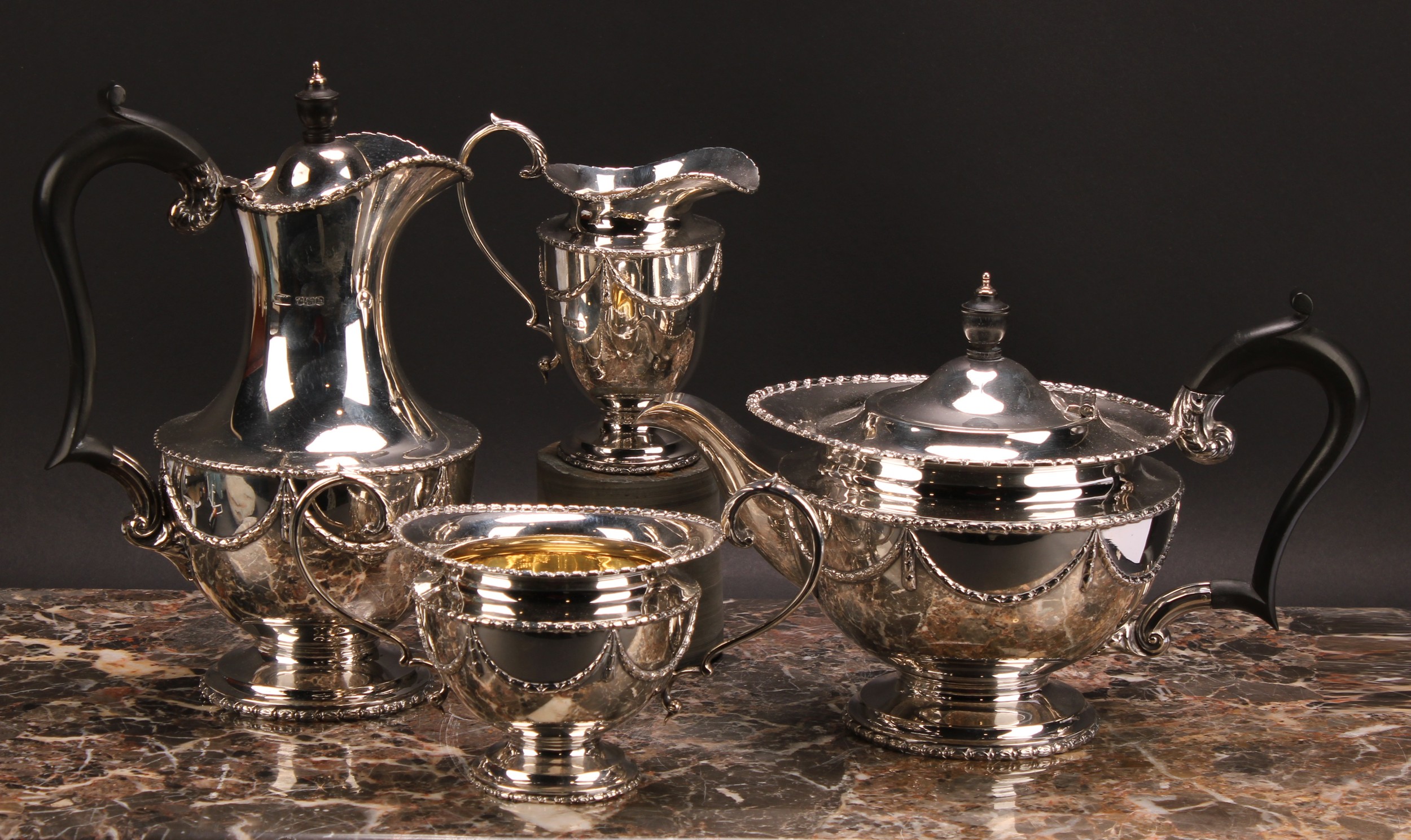 A George V Regency style silver four piece tea service, comprising tea pot, coffee pot, milk jug and sugar bowl, embossed with foliate swags, pattern number 2359, Robert Fead Mosley & Co, Sheffield 1925, approx. 62.5oz