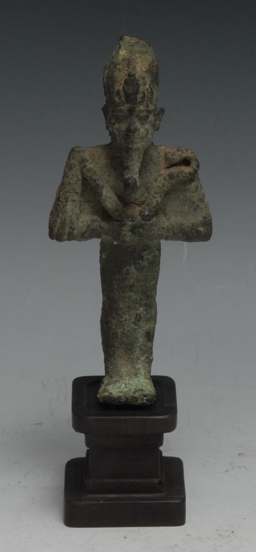 Antiquities - an Ancient Egyptian bronze figure, of Osiris, he stands, holding implements, 11cm high, Third Intermediate Period, c.1050 - 730 BC  Provenance: Antiquities - an Ancient Egyptian cartonnage sarcophagus fragment, 12cm x 7cm, late New Kingdom culture, 19th Dynasty, c.1292 - 1189 BC   Provenance: Acquired by the vendor from the private collection of Ken Mannion, Barton-upon-Humber 13/07/21, he having obtained it in exchange for work undertaken for the owner of Helios Gallery Antiquities. Purcased by them from a private collection in Dorset.