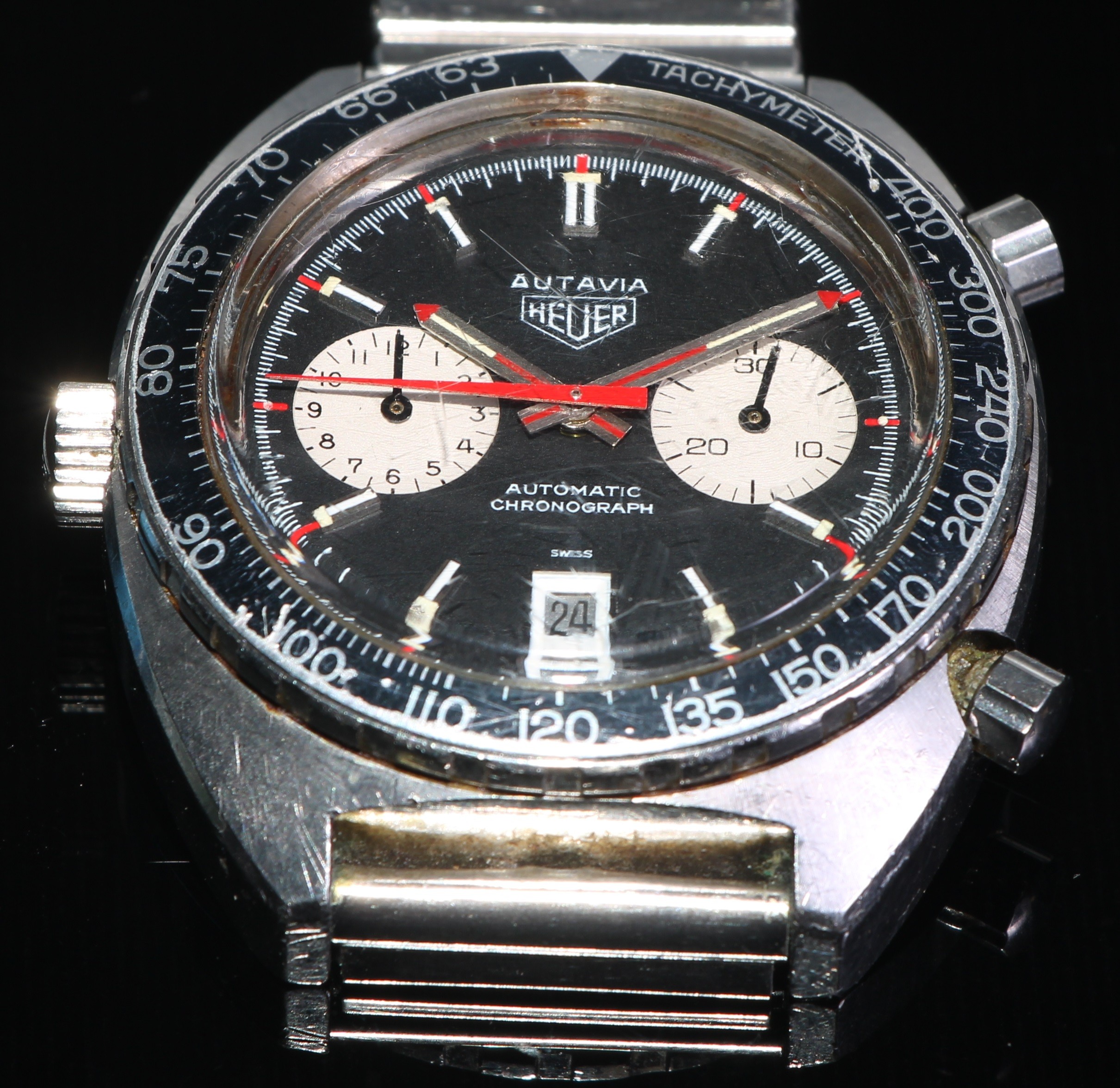 Heuer - Autavia, ref 1163, a stainless steel chronograph bracelet watch, no. 246191, black dial with silver sub dials, applied luminous silver baton hour markers, pointed steel hands with luminous inserts, black sub dial hands and red seconds recording hand, date aperture to 6 o’clock, black bezel with Arabic numeral, automatic movement, 17 jewels unadjusted, cal. 11, screw down case back, case, dial, crown, movement and bracelet signed, on a stainless steel bracelet with folding clasp, diameter 42mm, associated strap