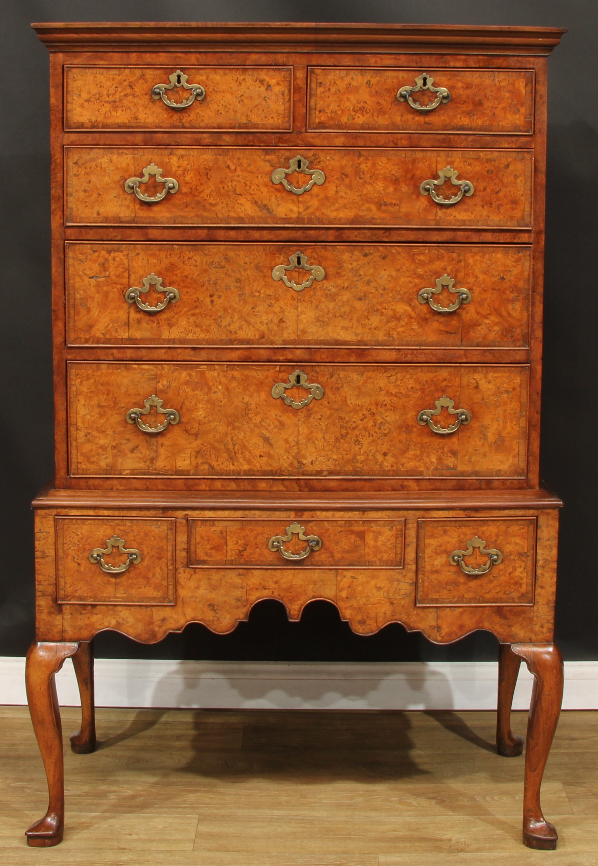 A George II burr walnut chest on stand, of two short and three long graduated oak crossbanded cockbeaded drawers, the base with three further drawers, shaped apron, cabriole legs, pointed pad feet, 160cm high, 105.5cm wide, 53.5cm deep, c.1740 with later renovations