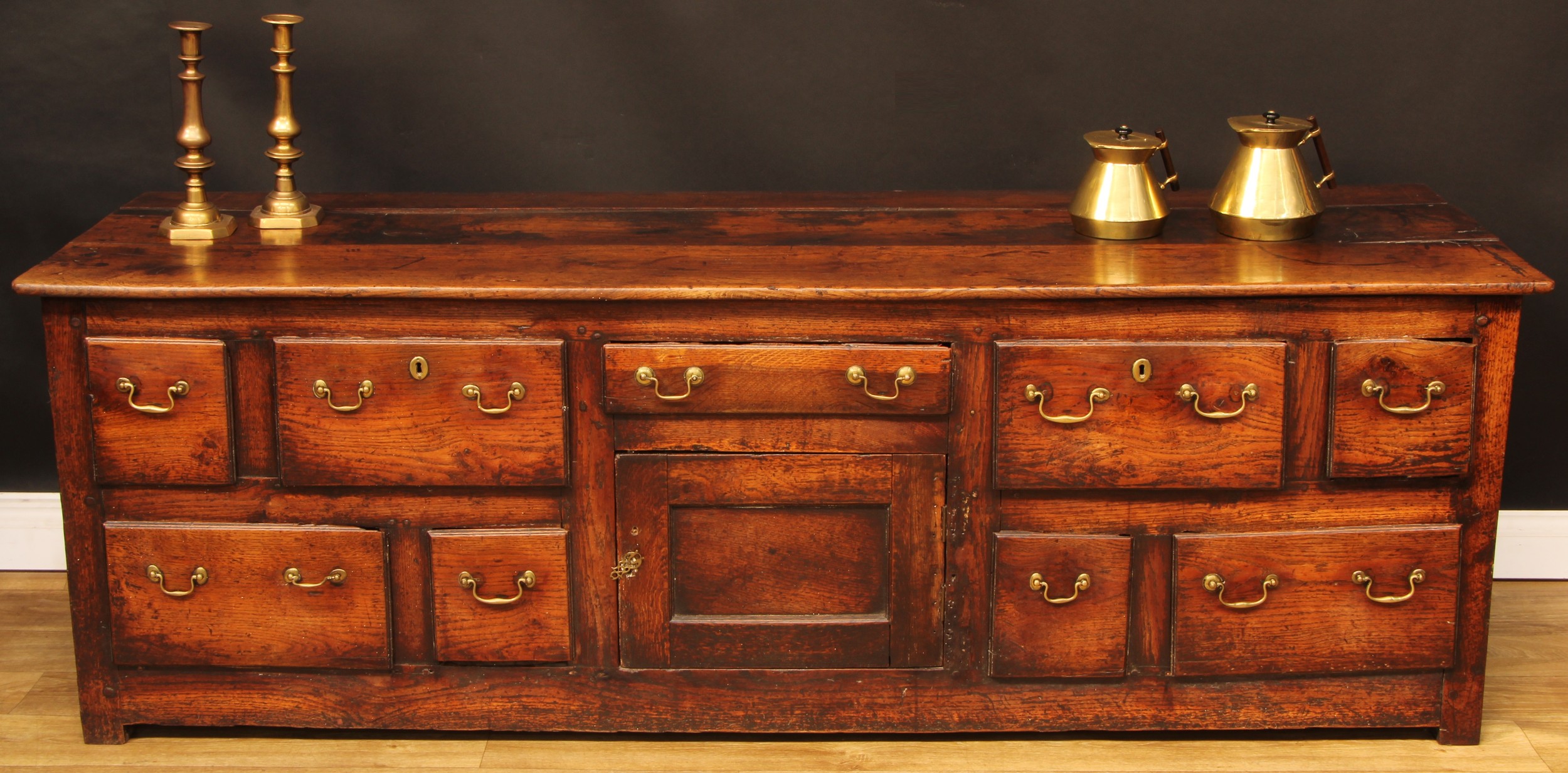 A George III vernacular oak low dresser, plank rectangular top above an arrangement of drawers and a panel door, 70cm high, 206cm wide, 62cm deep, c.1790