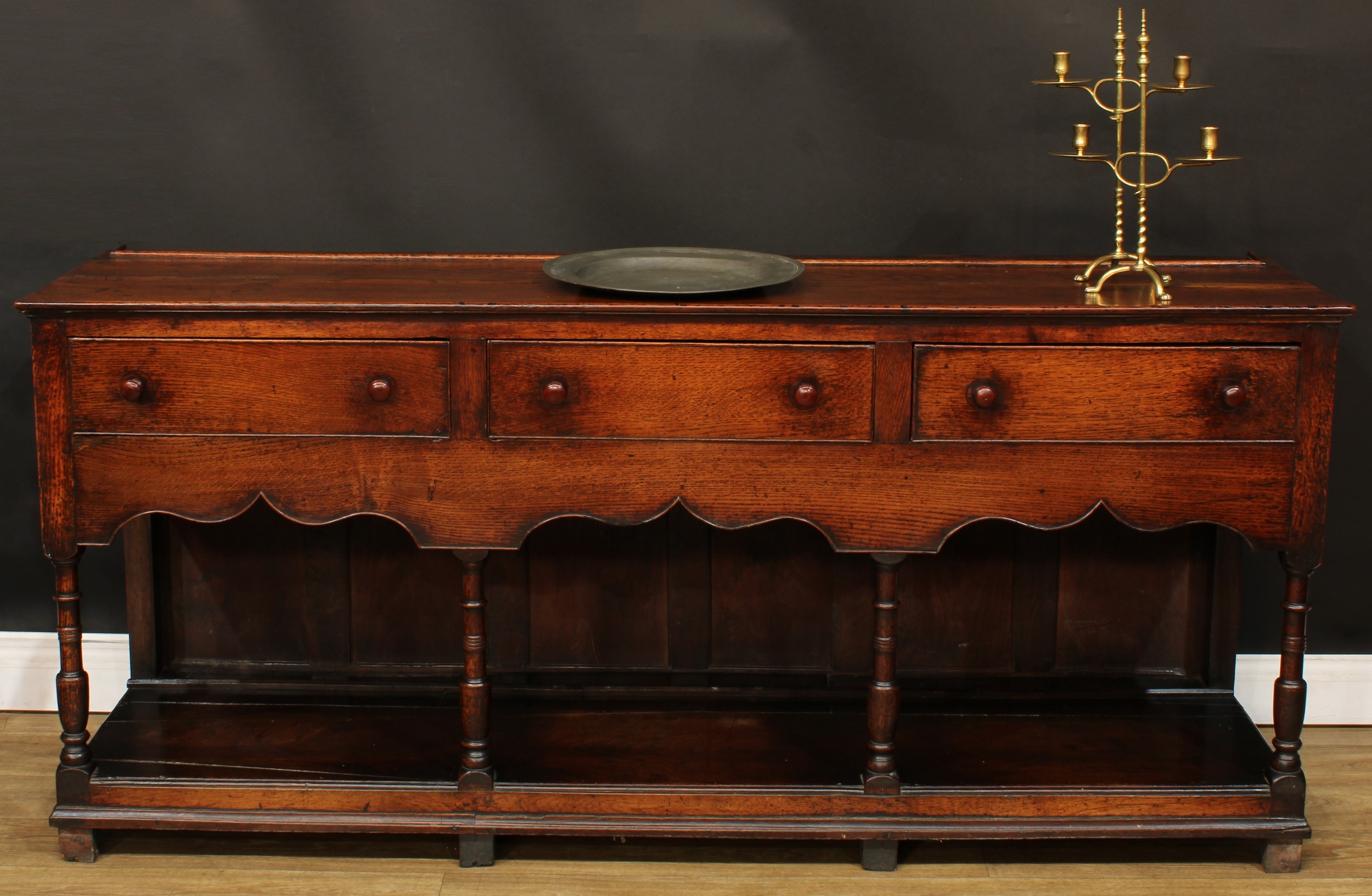 A George III oak low potboard dresser, slightly oversailing plank rectangular top, above three cockbeaded frieze drawers, shaped apron, turned supports, open undertier, block feet, 83.5cm high, 182.5cm wide, 47.5cm deep, c.1800