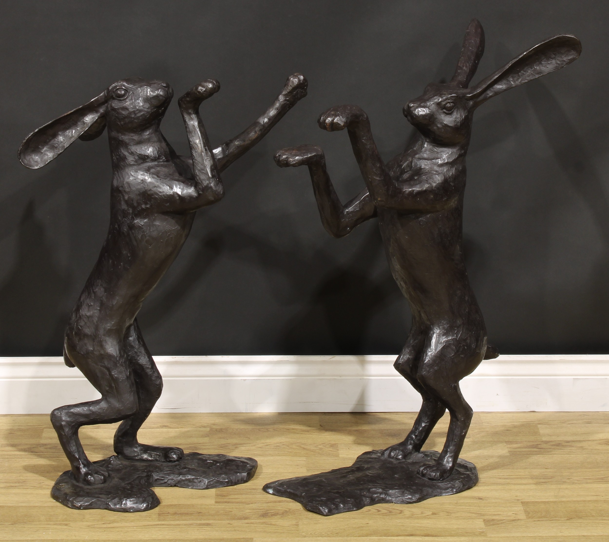 A pair of contemporary dark patinated bronzed metal models, boxing hares, the largest 85cm high, the other 77cm high