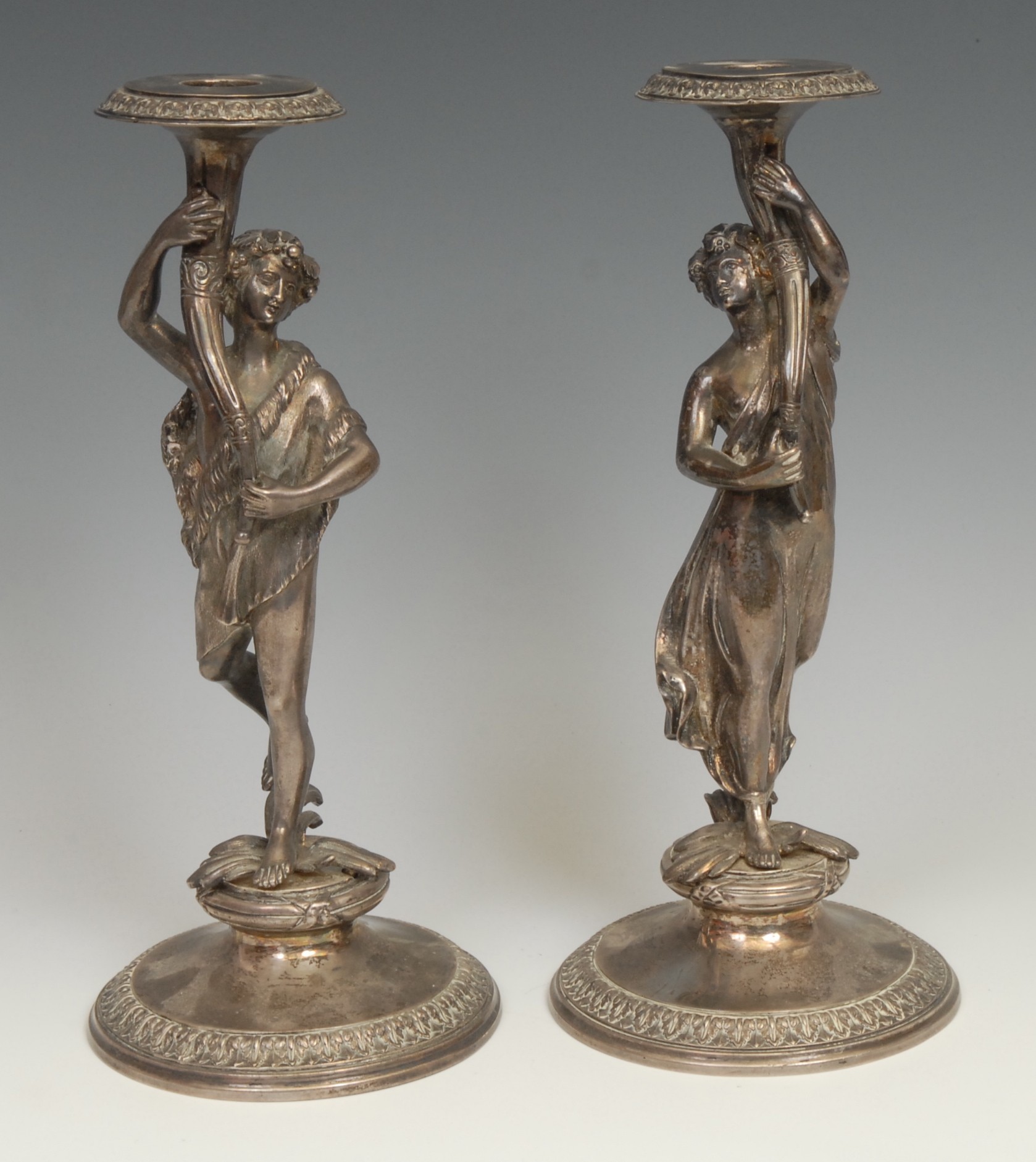 A pair of sculptural Victorian silver figural candlesticks, cast as a Bacchic reveller and  maenad raising aloft a cornucopia, domed circular bases with acanthus borders, 25.5cm high, Stephen Smith & Son, London 1865