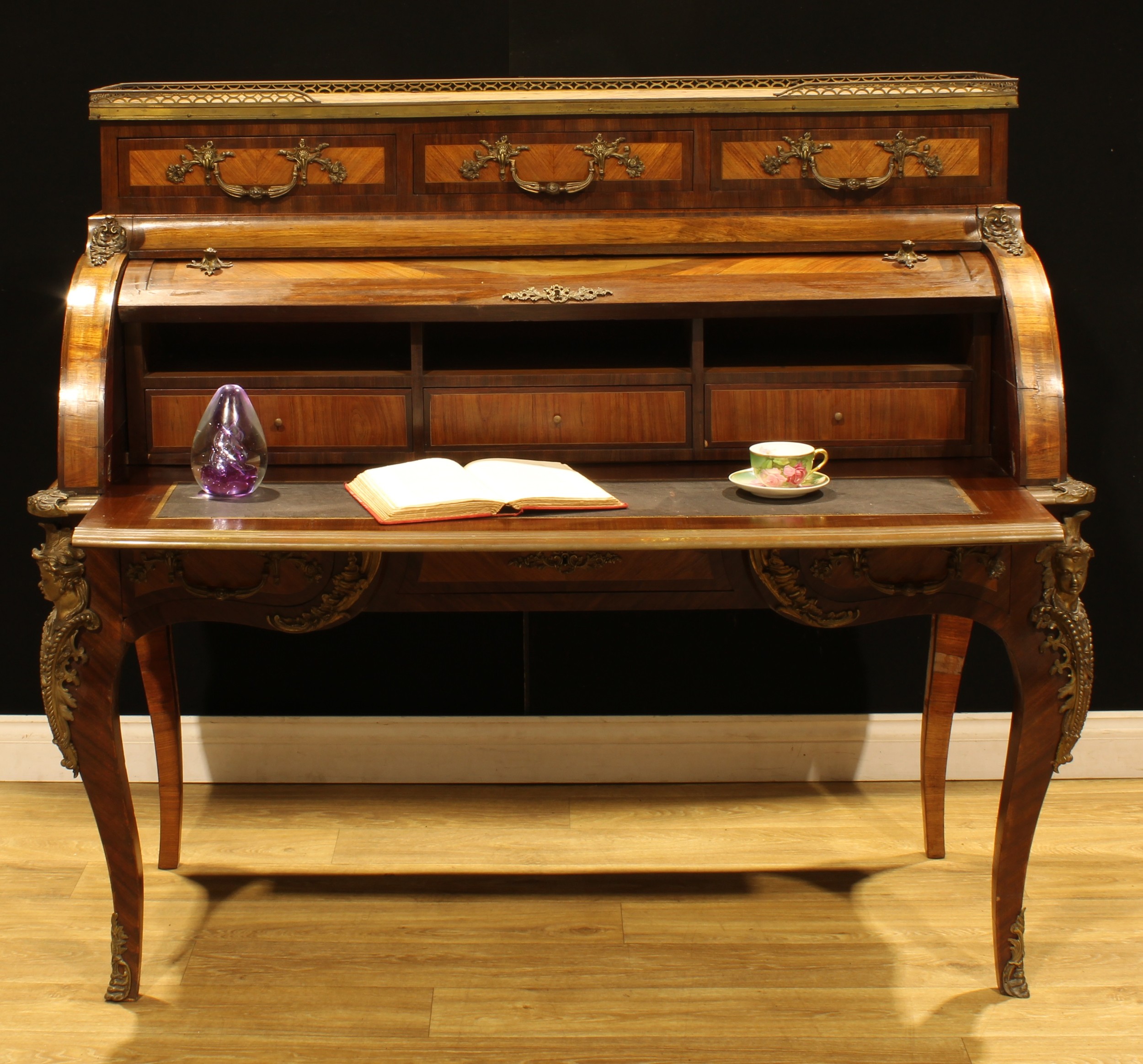 A large Louis XV Revival French gilt metal mounted kingwood, rosewood and marquetry bureau à cylindre, marble top with pierced gallery above three small drawers, retractable front inlaid with a musical trophy and enclosing a fitted interior and sliding writing plateau, further drawers to frieze, serpentine legs, 127cm high, 143cm wide, 70cm deep, early 20th century