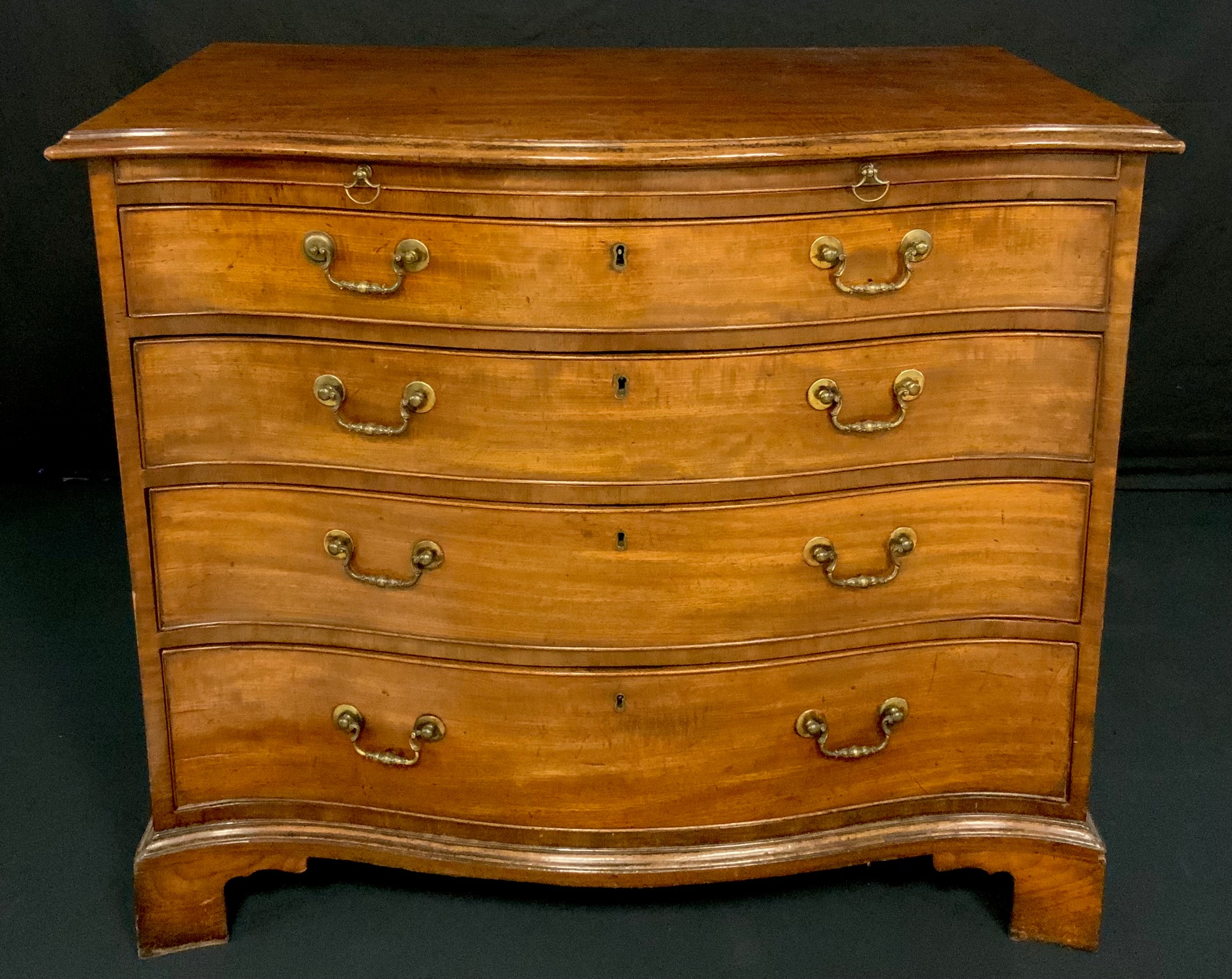 A George III mahogany serpentine bachelor’s chest, fiddleback top above a slide and four long graduated drawers, skirted base, bracket feet, 83cm high, 96cm wide, 57cm deep, c.1770