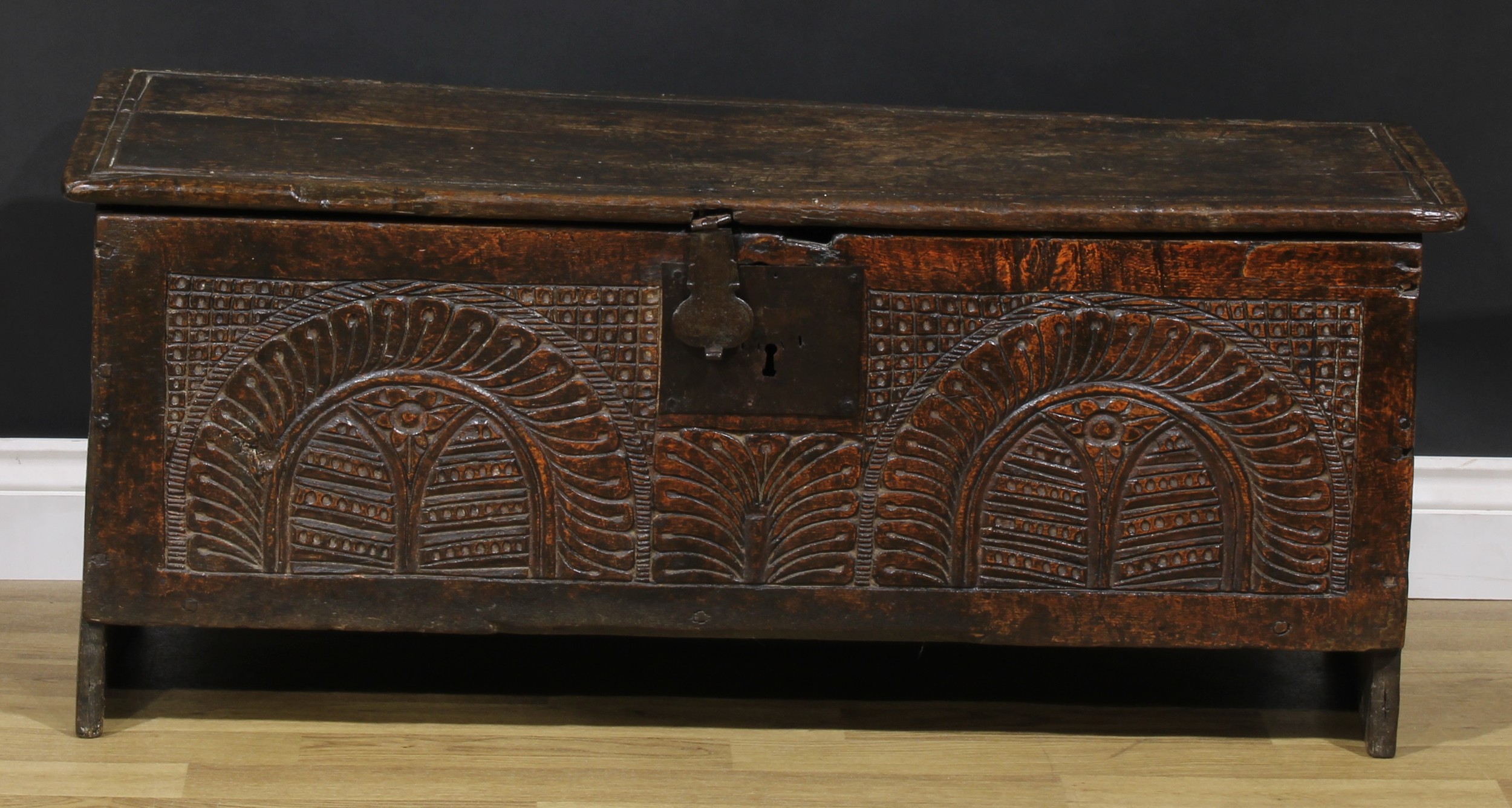 A 17th century oak six plank chest, of boarded construction, hinged top, the front carved with two leafy lunettes centred by a naive anthemion, 45cm high, 106cm wide, 37cm deep, c.1650