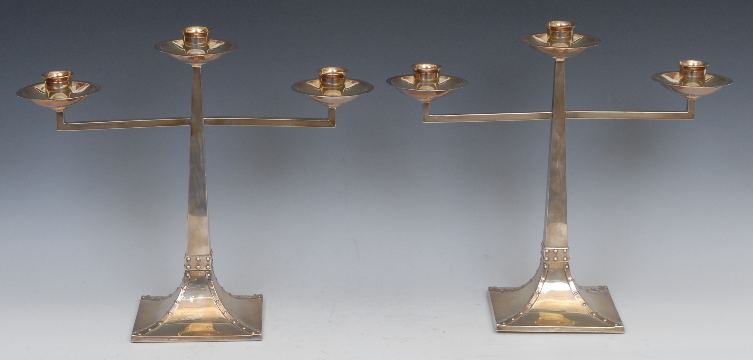 A pair of Arts and Crafts silver candelabra,  the design attributed to Jan Eisenloeffel (1876-1957), tapering square columns , spreading square bases with faux riveted borders ,32cm high, James Dixon & Sons, Sheffield 1905