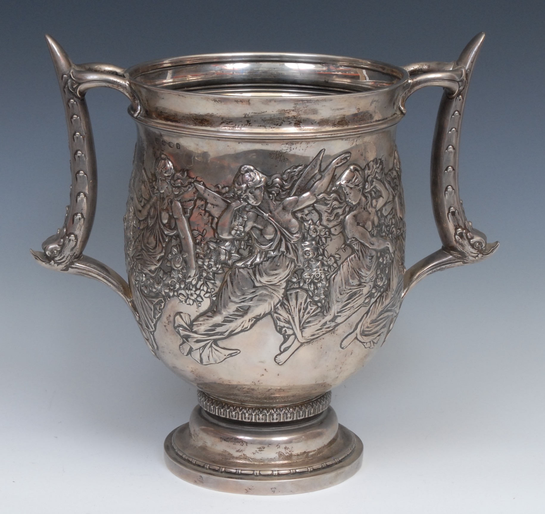 Tiffany & Co - a substantial American silver two-handled loving cup, chased with fairies gathering blooms, 11.5 pint capacity, dolphin handles, 30cm high, import marks for Tessiers Ltd, London, 1934, 1998g