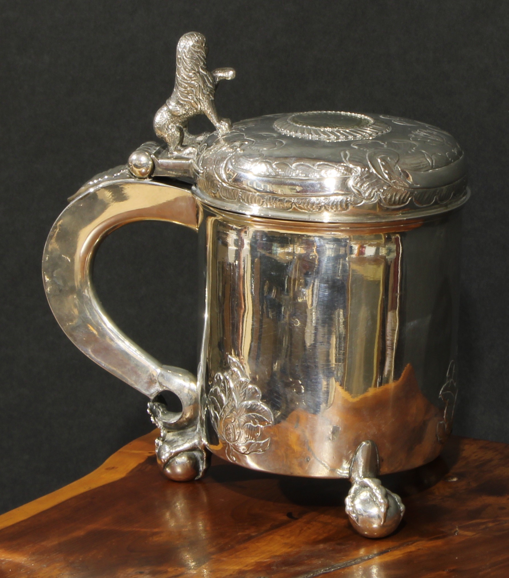A Norwegian silver peg tankard, hinged domed cover with rampant lion thumbpiece, chased with leafy scrolls and set with a coin, scroll handle, ball and claw feet, gilt interior, 23cm high, maker's mark TT, the coin dated 1795, 1070g
