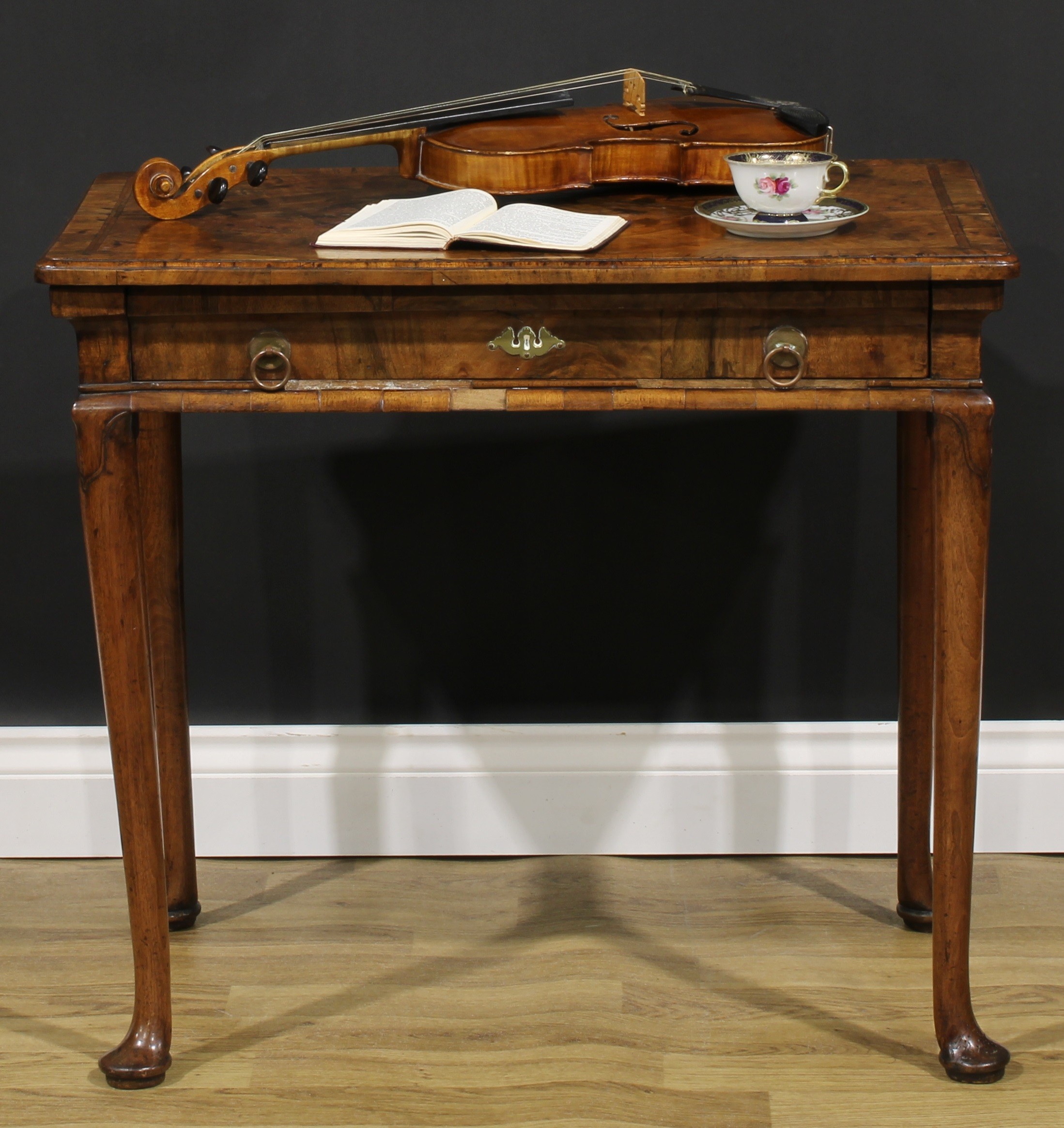 A George II walnut side table, featherbanded rounded rectangular top with moulded edge above a long frieze drawer, straightened cabriole legs, pad feet, 67.5cm high, 76.5cm wide, 47cm deep, c.1750