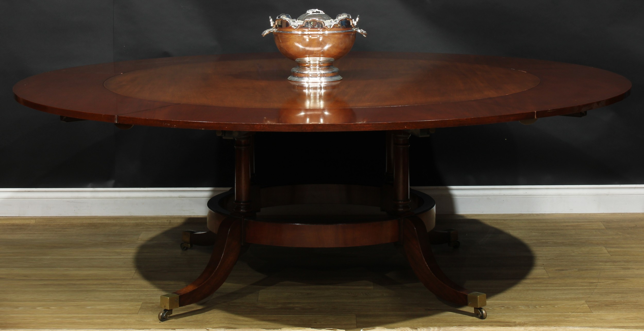 A Regency Revival mahogany extending dining table, in the manner of Johnstone, Jupe & Co and William Tillman, circular top with five additional leaves, turned supports, sabre legs, brass casters, 72.5cm high, 153cm extending to 214.5cm diameter