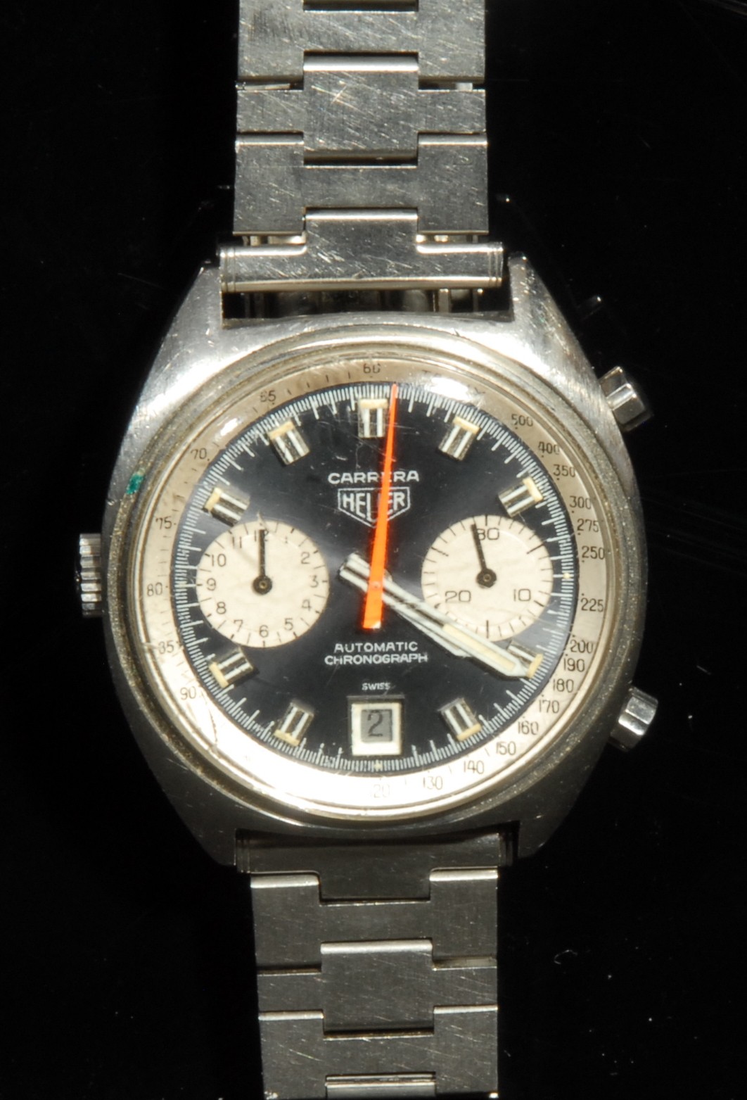 A gentleman's Heuer Carrera automatic chronograph stainless steel wristwatch, black non-reflective dial, luminous baton indicators and rotating hands, orange centre seconds hand, Tachy bezel with Arabic numerals, pair of subsidiary dials, date aperture, replacement stainless steel bracelet strap, original Heuer clasp present, winder with Heuer logo, paper label, c.1970