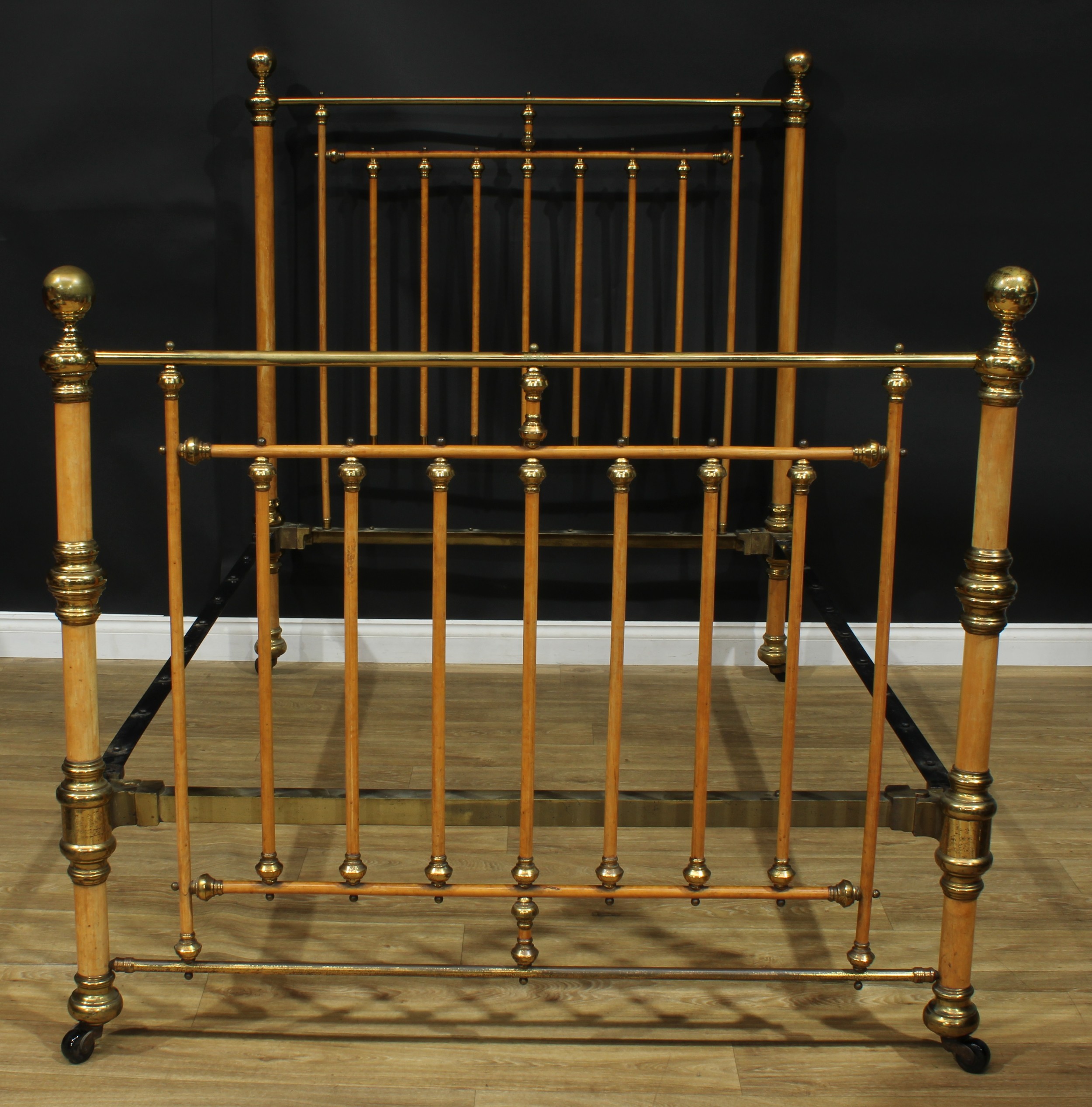 An unusual late 19th century brass and birch double bed, globe finials, ceramic casters, the headboard 162.5cm high, the internal 192cm x 139cm