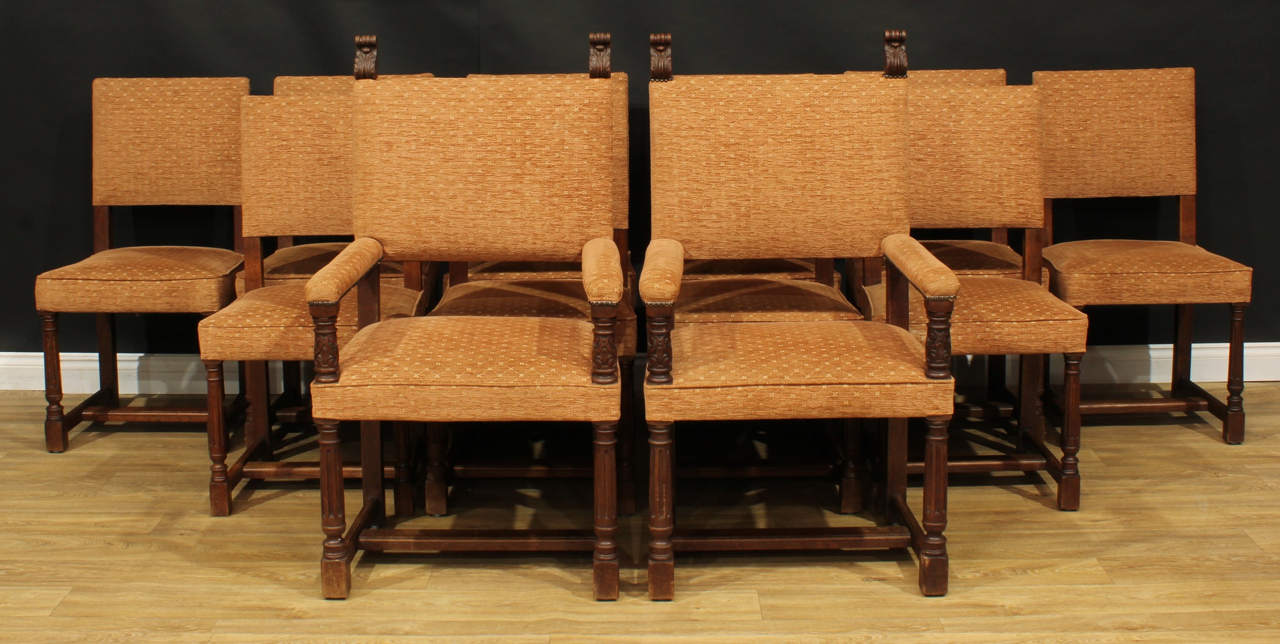 A set of twelve late Victorian Cromwellian Revival oak dining chairs, by Howard & Sons, comprising ten side chairs and a pair of carvers, the carvers and six side chairs stamped 3874 9082, HOWARD & SONS LTD, BERNERS ST, the other four unmarked, the side chair 99.5cm high, 52.5cm wide, the seat 44cm deep, the carver 117.5cm high, 67cm wide, the seat 52cm wide and 44cm deep