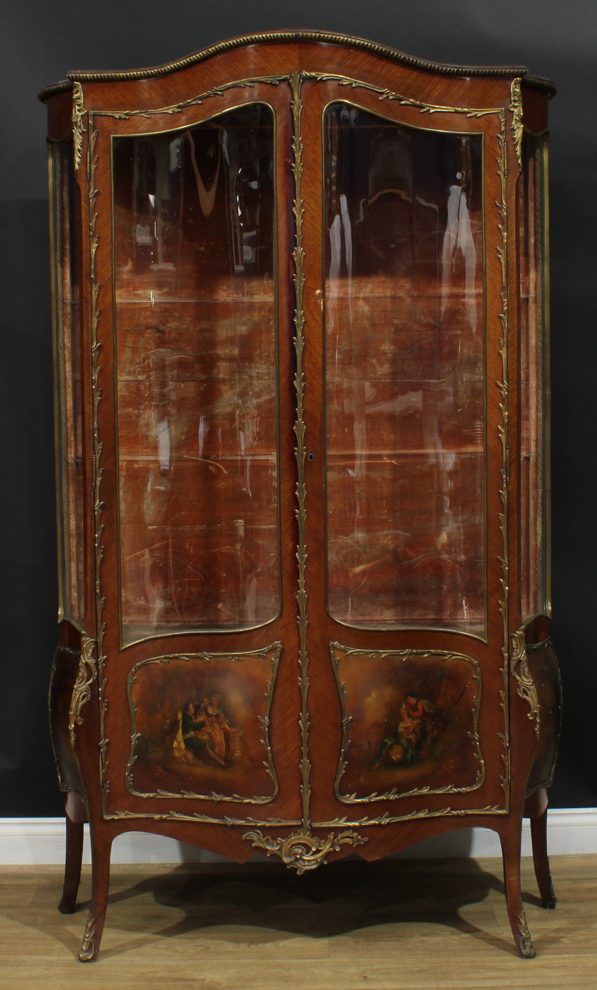 A Louis XV Revival gilt metal mounted serpentine Vernis Martin vitrine, dome top above a pair of three-quarter glazed doors, the lower panels painted with courting couples, shaped apron, outswept legs, 198cm high, 118cm wide, 39cm deep, c.1900