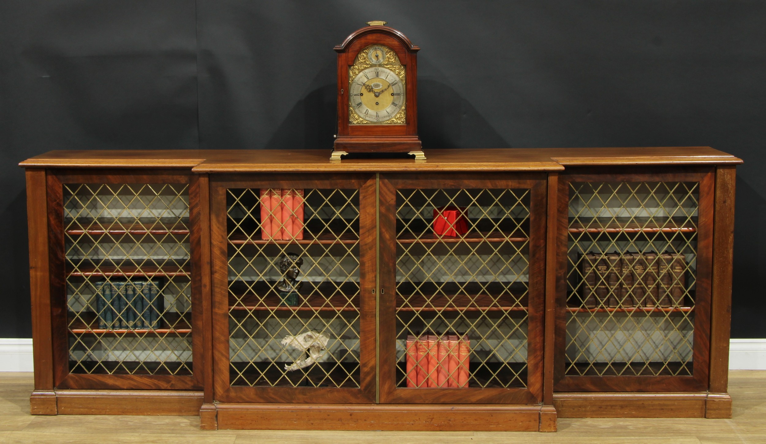 A Regency mahogany breakfront low library bookcase, by Graygoose, 57 Gt Queen St, stamped, slightly oversailing top with moulded edge above four doors, each set with a brass grille and enclosing adjustable shelves, plinth base, 89.5cm high, 242cm wide, 45cm deep, c.1820