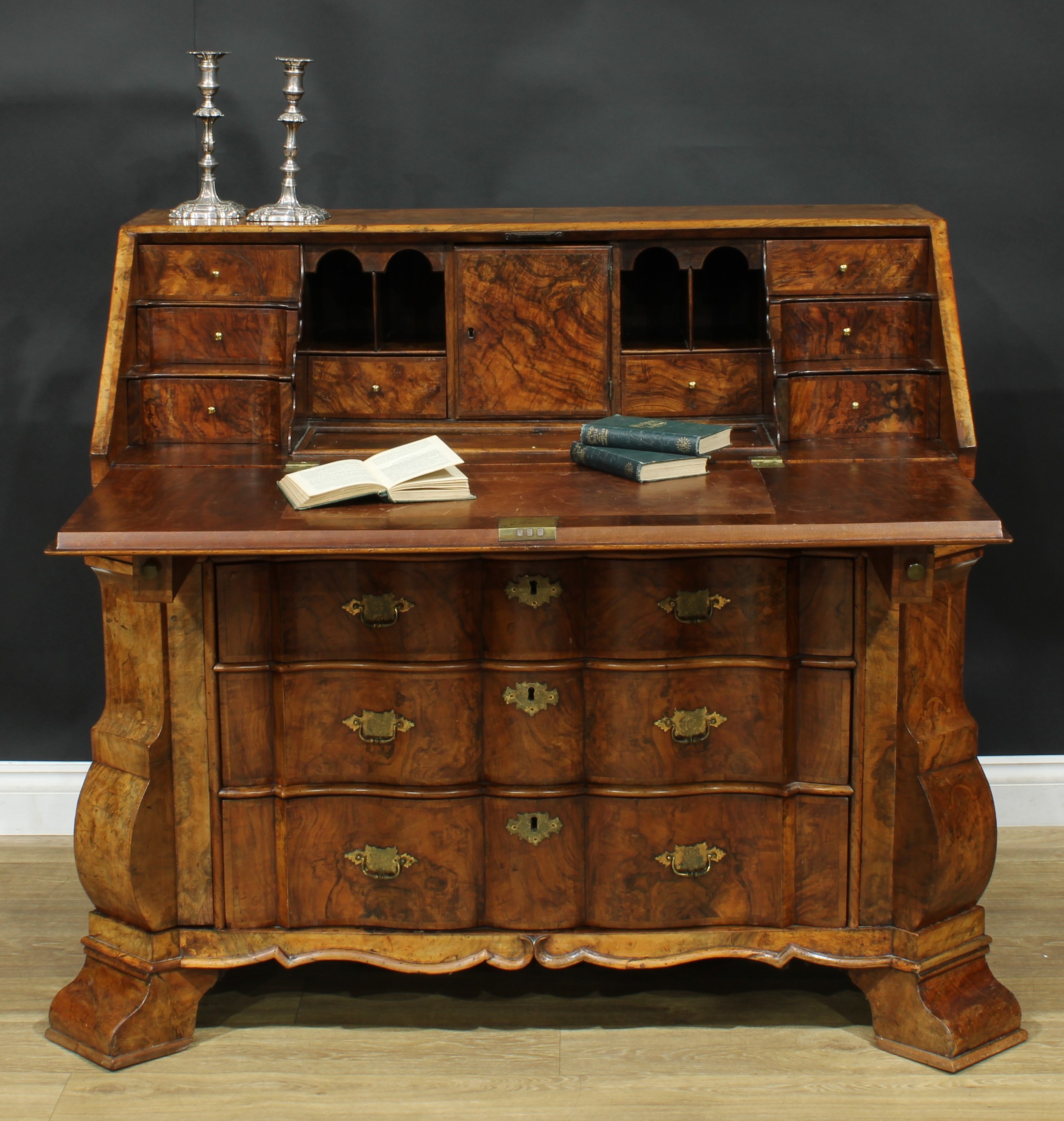 An 18th century Dutch walnut arc-en-arbalète bureau, fall front with reading ledge enclosing an inset writing surface, a well, a door, small drawers and pigeonholes above three long drawers, flanked by hinged canted angles, each enclosing four ‘secret’ drawers, bracket feet, 107.5cm high, 133cm wide, 69cm deep