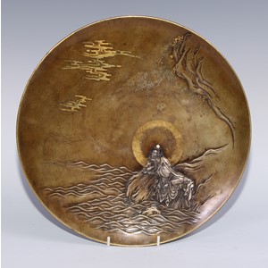A Japanese bronze circular charger, applied and inlaid in silver and mixed metal with Guanyin on a rock at the edge of the coast, 32.5cm diam, signed and inscribed to verso, 32.5cm high, Takaoka, Meiji period