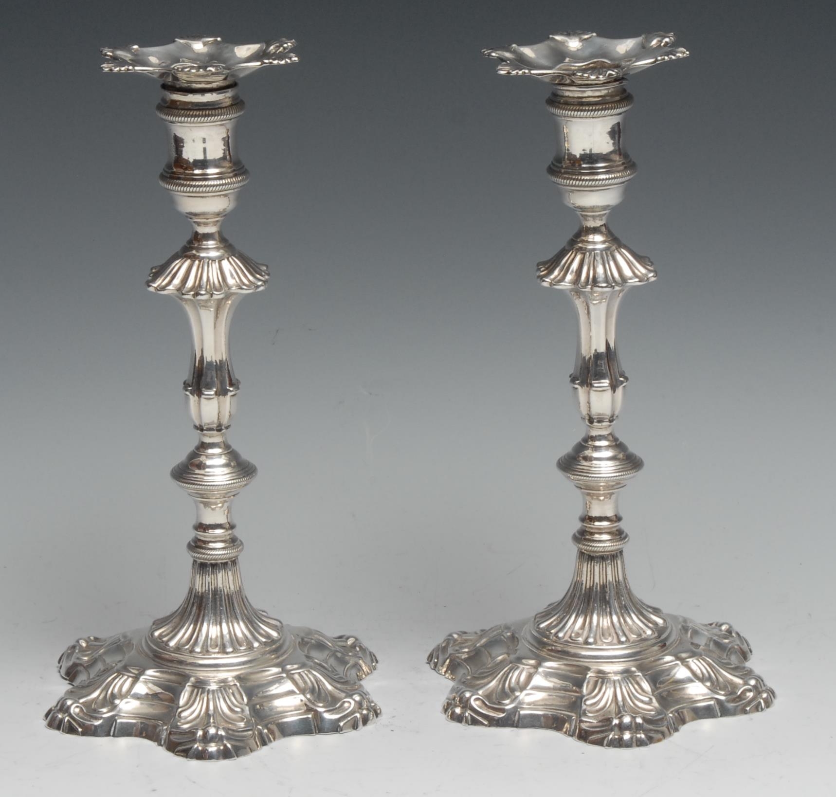 A pair of George II cast silver table candlesticks, reel shaped sconces with nozzles, knopped pillars, hexafoil shell bases, 23.5cm high, James Morison, London 1759, 1400g