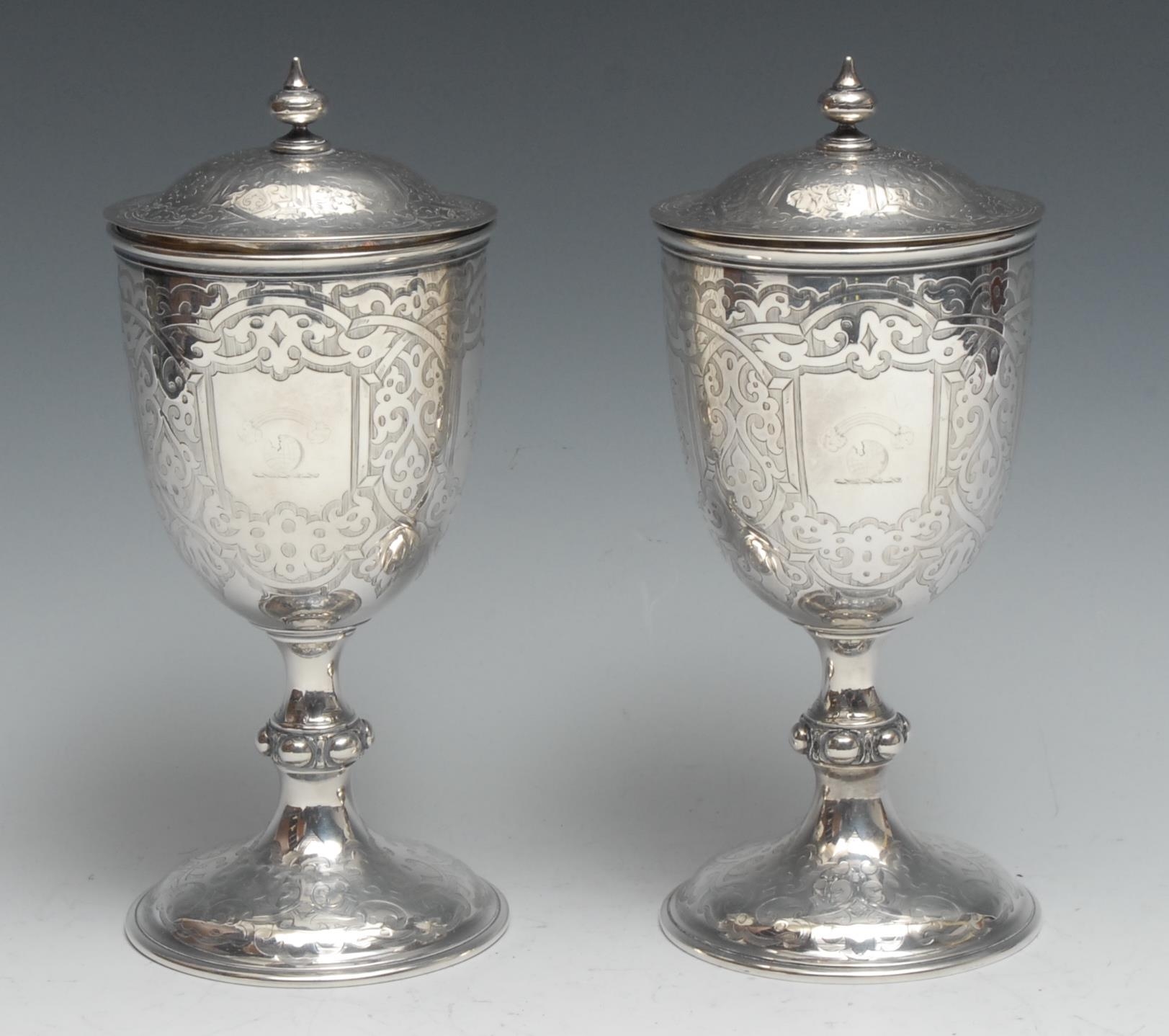 A pair of Victorian Gothic Revival silver pedestal goblets and covers, engraved overall with strapwork, knopped stems, domed bases, 22.5cm high, Robert Hennell, London 1861, 758g  Heraldry: Crest of Hope, the family of the Marquis of Linlithgow & Earl of Hopetoun