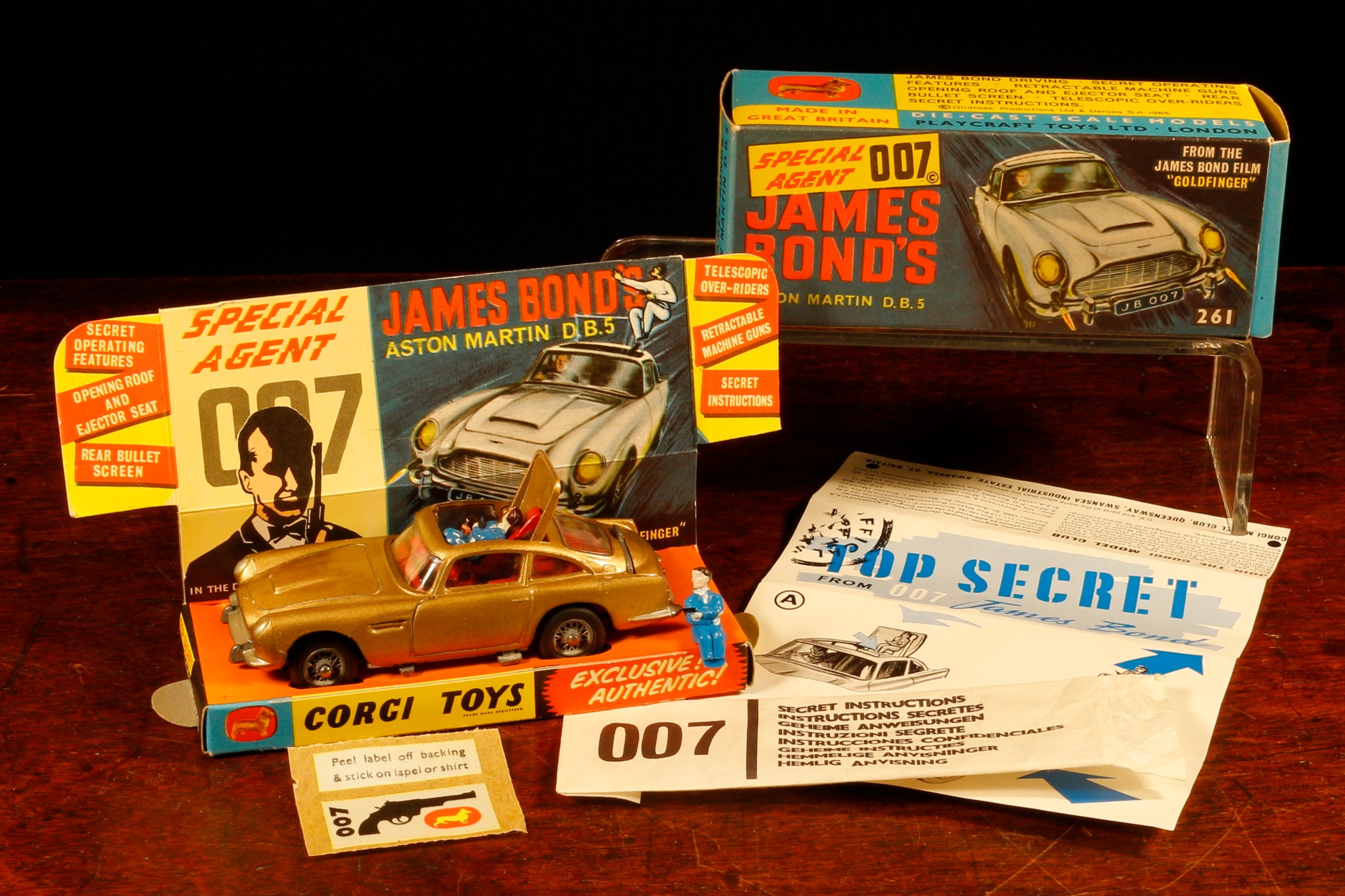 Corgi Toys 261 Special Agent 007 James Bond's Aston Martin D.B.5. from the James Bond film "Goldfinger", gold body with red interior, wire spoke wheels, James Bond and seated plastic bandit figure to interior, boxed with original inner cardboard pictorial display stand, 'secret instructions' in packet, 007 lapel badge on backing paper and spare plastic bandit figure
