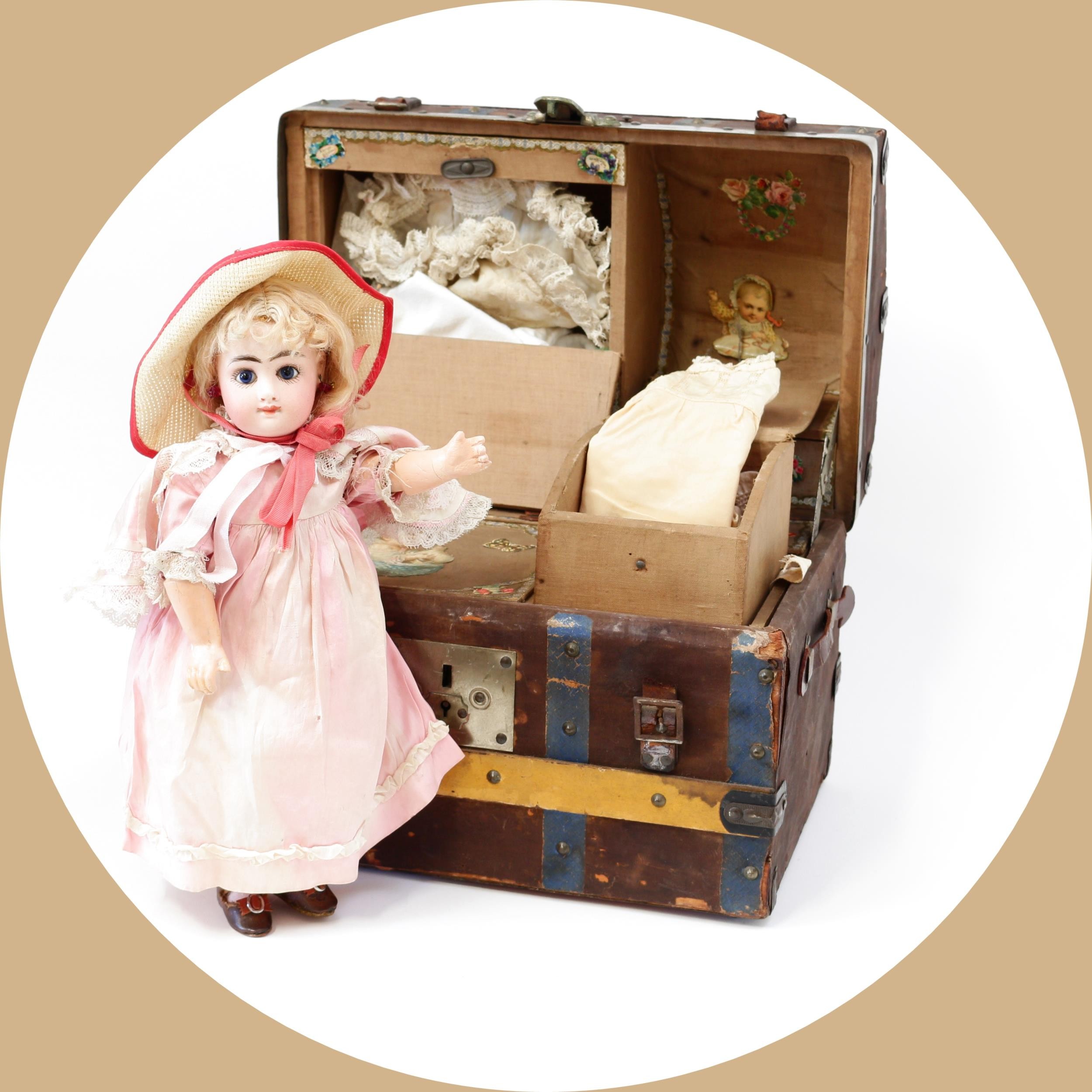 Toys From The Attic Part II - a Fleischmann & Bloedel Eden Bèbè bisque head and painted composition bodied doll, the bisque head inset with fixed blue glass eyes, painted features including thick feathered brown eyebrows and fine eyelashes, blush cheeks, moulded and painted red lips, blonde wig on pate, pierced ears, impressed marks 'EDEN BEBE, H., PARIS', 35.5cm high; together with a brown linen covered domed top travel trunk of small proportions, the fitted interior with various compartments and a single lift out tray with various doll clothing and accessories (quantity)