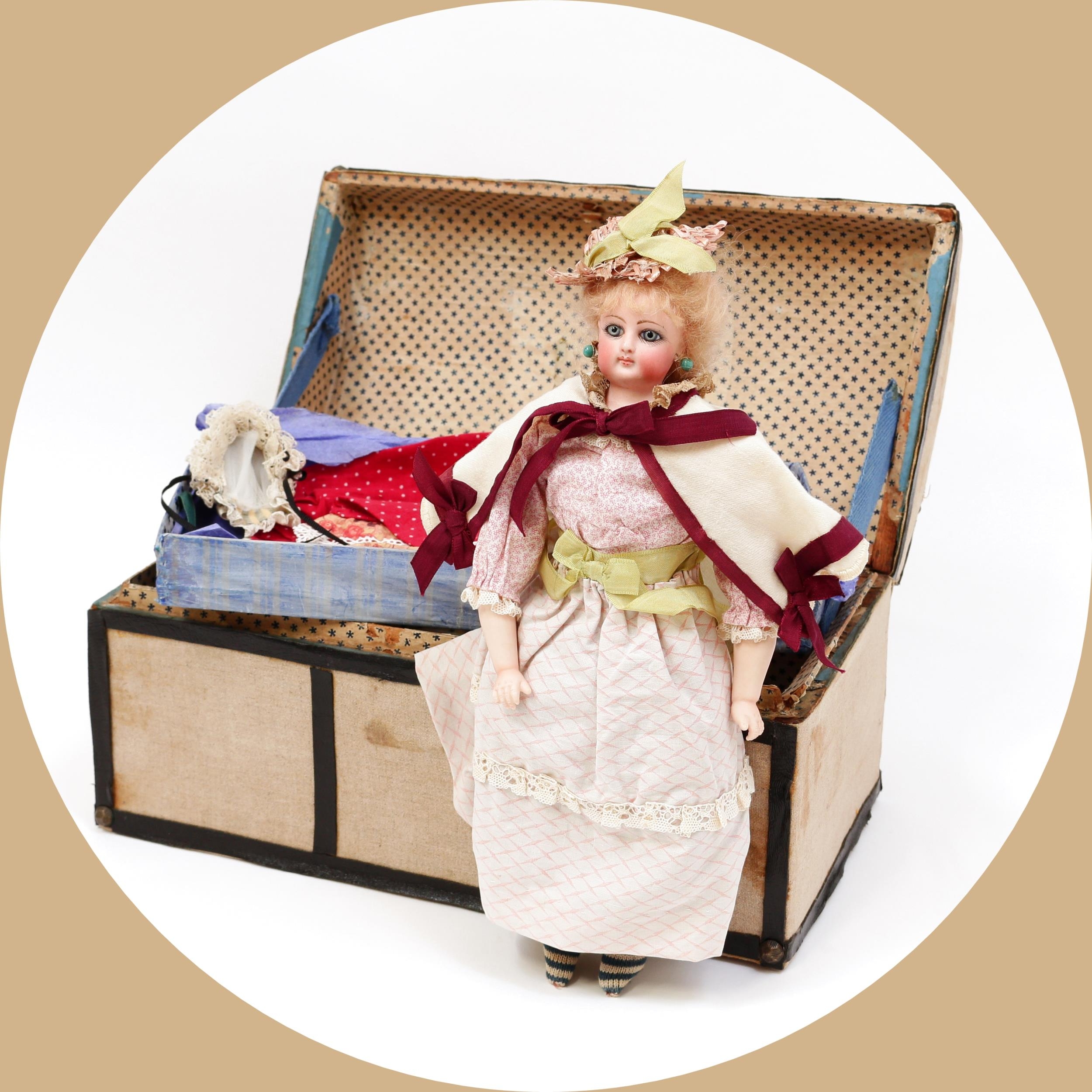 Toys From The Attic Part II - a Francois Gaultier (France) bisque shoulder head French Poupée de Mode or fashion doll, the bisque shoulder head inset with fixed blue glass eyes, painted features including feathered eyebrows, fine eyelashes, blush cheeks and red lips, pierced ears, blonde wig on cork pate, impressed marks 'F o G', partially stuffed cloth body with bisque lower arms, 33cm high; together with a canvas covered domed top travel trunk of small proportions, the interior fitted with a single lift out tray with various doll clothing (quantity)