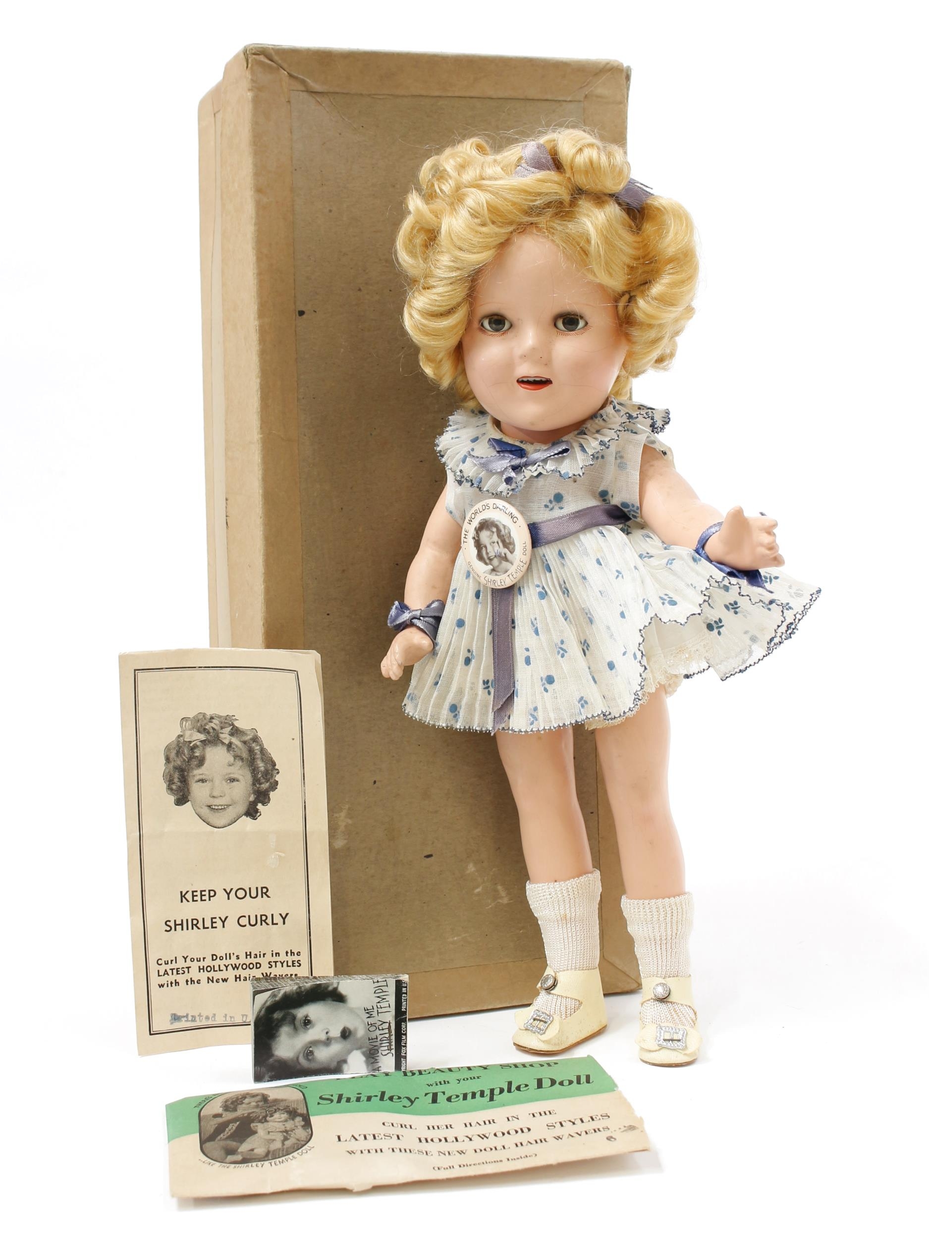A 1930's Reliable Toy Company (Canada) Shirley Temple composition head and painted composition bodied doll, the painted composition head with weighted sleeping brown eyes, painted features, open mouth revealing upper teeth, blonde wig, embossed mark to the back of the head, 33cm high, boxed with literature including flick book and pin badge