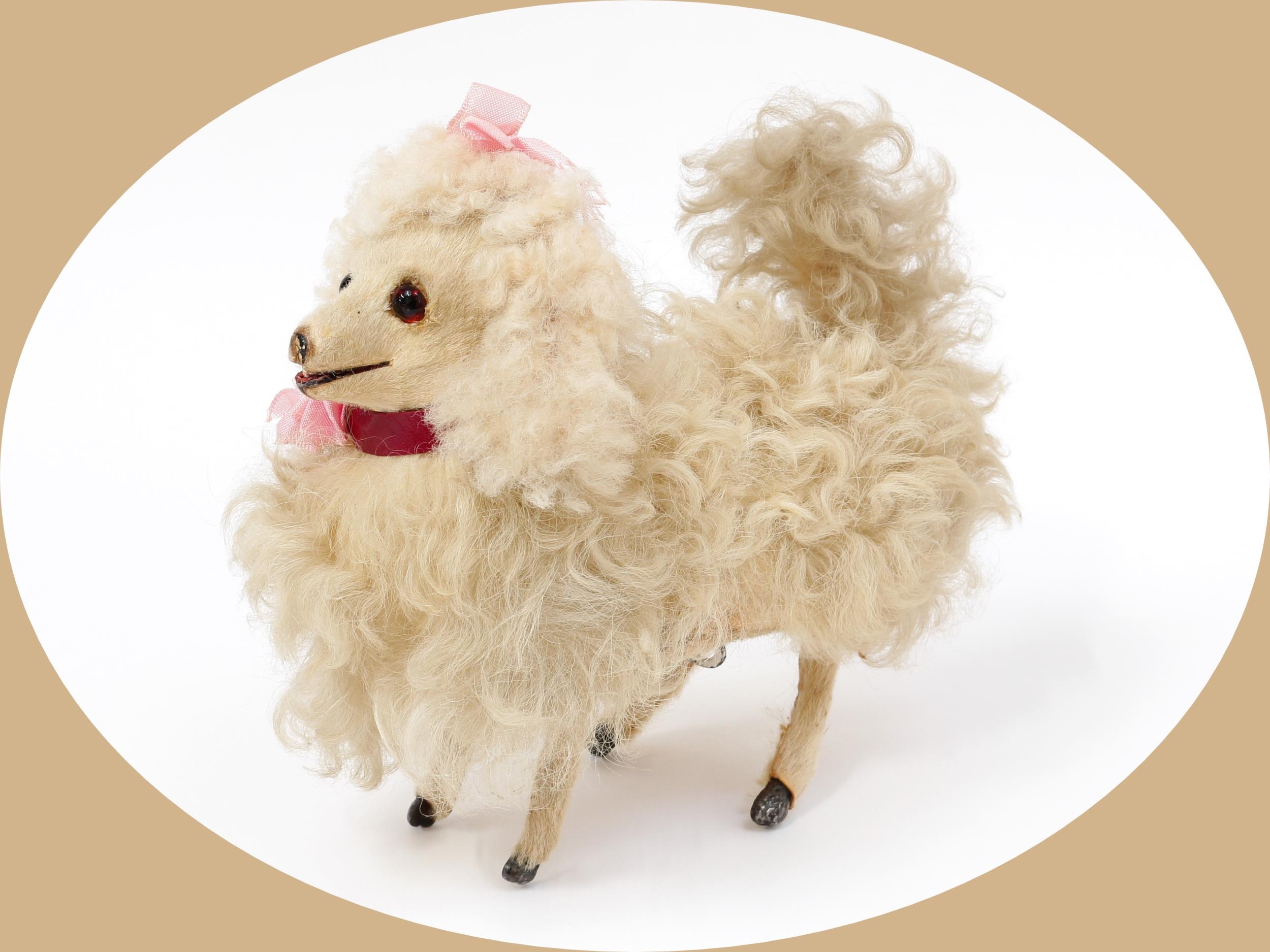 Toys From The Attic Part II - Automata - a late 19th century French automaton toy Poodle Dog, attributed to Elie Martin (France), the papier-mâché body covered with white faux fur, shaved face inset with amber and black glass eyes with partially open mouth, pink bow to head, fixed key wind mechanism to underside, 20cm long