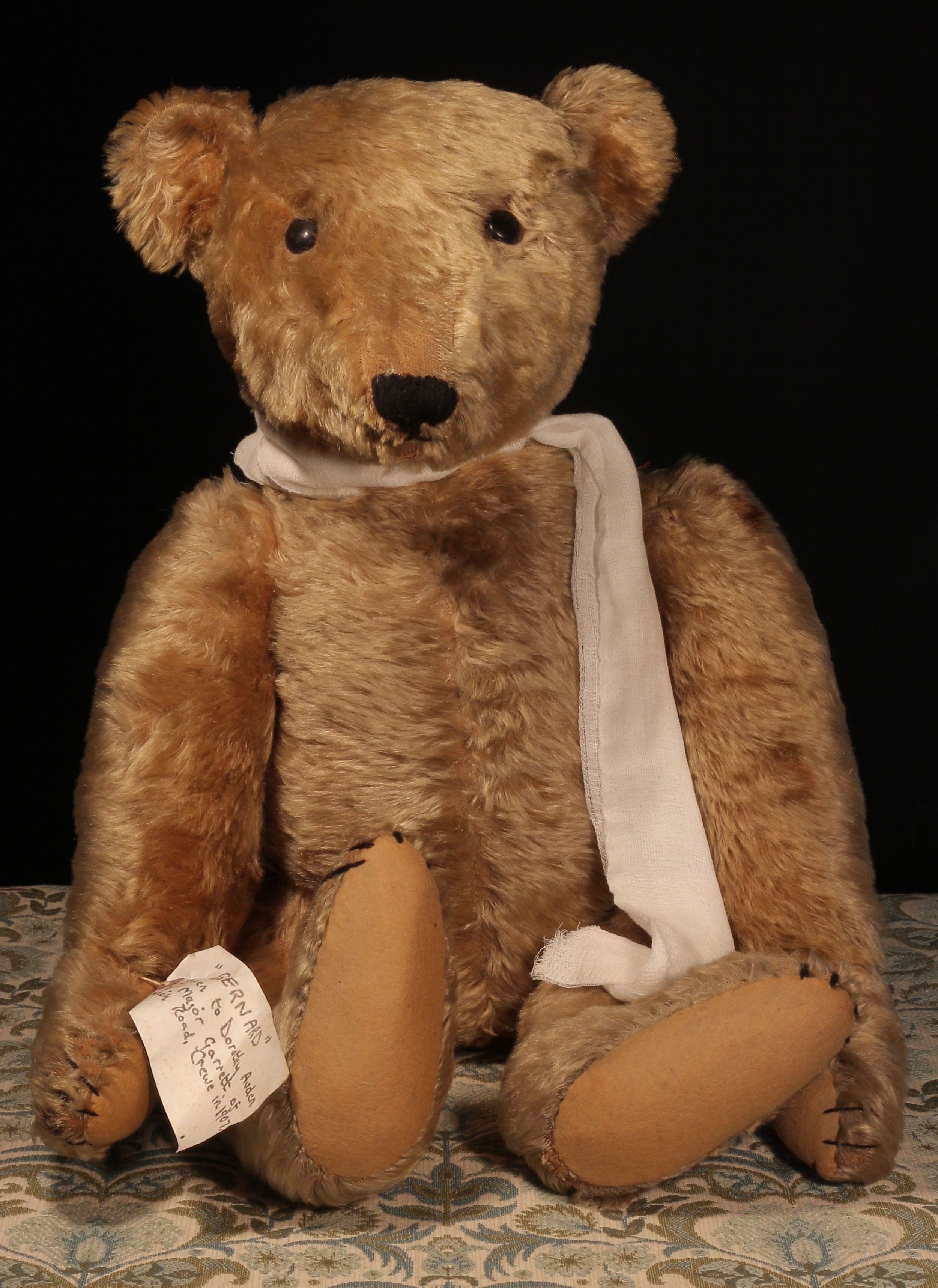 A large early 20th century jointed golden mohair teddy bear, attributed to Steiff (Germany) and affectionately named Bernard, large black boot button eyes,  pronounced snout with vertically black stitched nose and mouth, large elongated limbs, beige felt pads to hands and feet with black stitched claws, 71cm high  Provenance - The teddy bear is accompanied with a hand written tag around his arm which reads "BERNARD, given to Dorothy Auden by Major Garrett of Nantwich Road, Crewe in 1907".