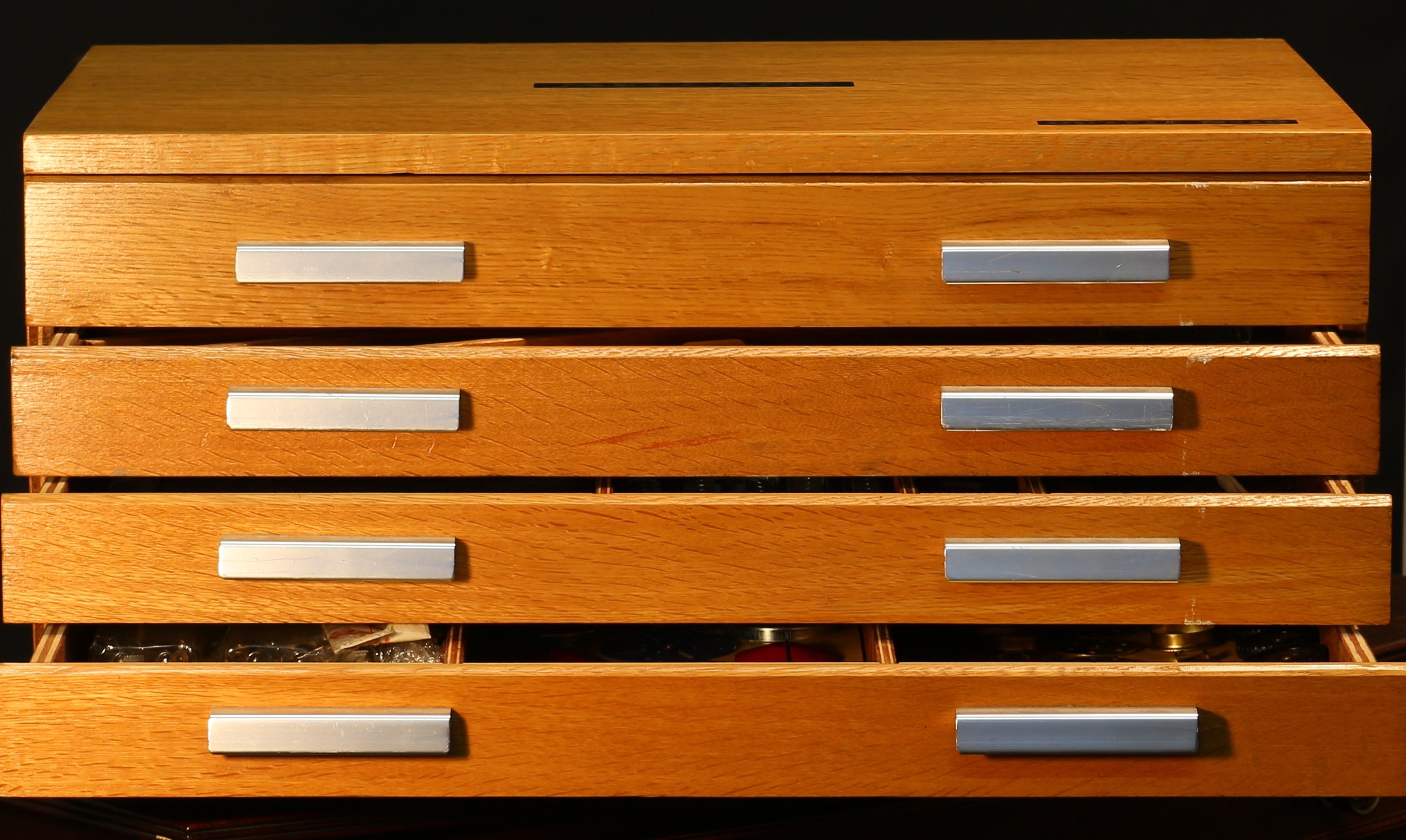 Model Engineering and Constructional Toys - a Meccano outfit No.10, comprising various yellow and blue components, parts and accessories, most of which are still cotton-tied down in place on inner cardboard display pieces, housed in a four drawer oak veneered Meccano cabinet, 28.5cm high, 60.5cm wide, 40cm deep; various Meccano literature a Meccano No.10 instructions wallet