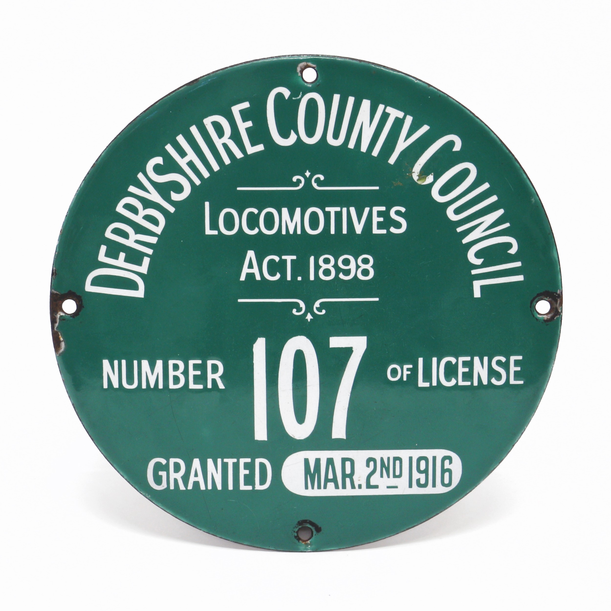 Derbyshire Interest - a single sided circular enamel license plate, white lettering on a green ground 'DERBYSHIRE COUNTY COUNCIL, LOCOMOTIVES ACT.1898, NUMBER 107 OF LICENSE, GRANTED MAR.2ND 1916', 20cm diameter  Provenance: This sign was originally on one of the flour mill steam lorries at Greensmiths flour mill, Burton upon Trent
