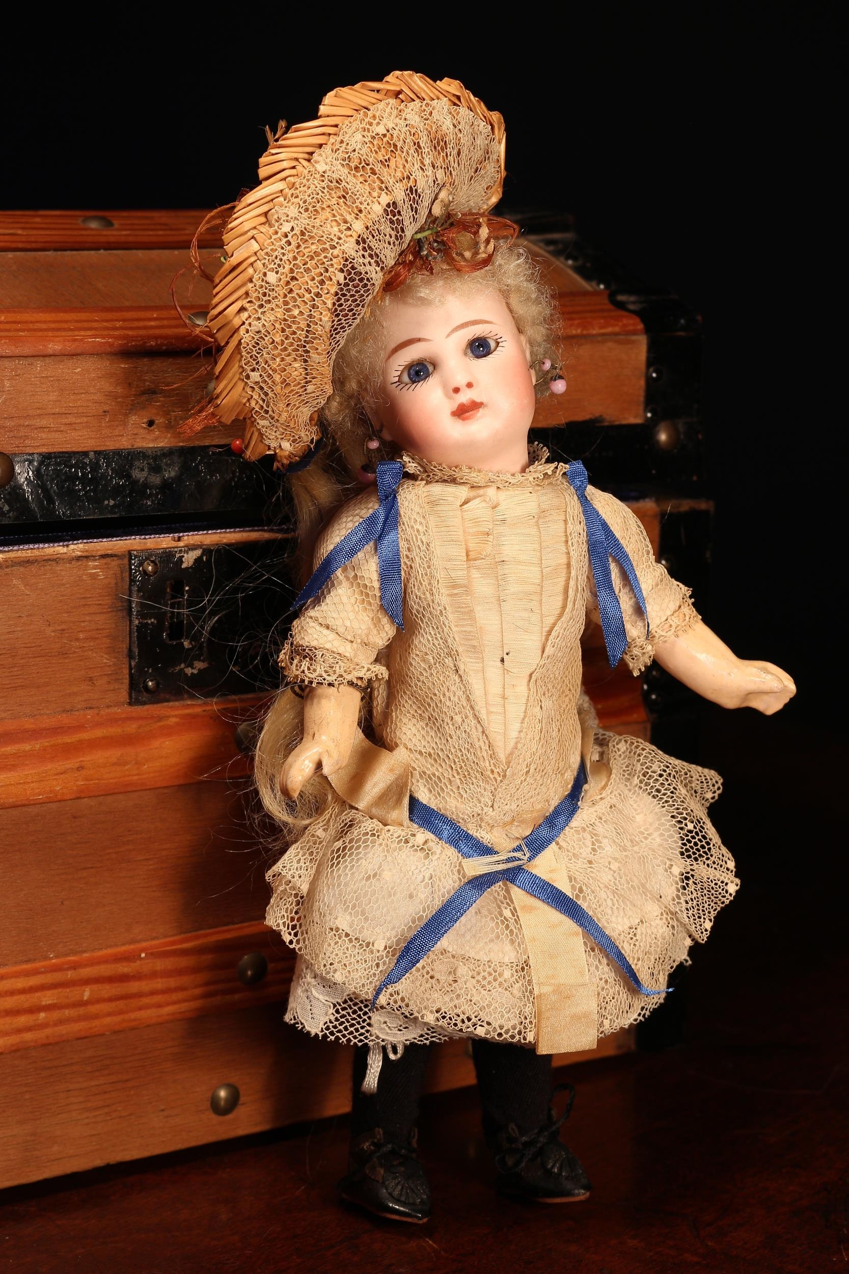 A Jules Nicholas Steiner (France) bisque head and jointed painted composition Bébé doll, the bisque head with inset fixed blue glass eyes, painted features including brown eyebrows, fine eyelashes and red lips, pierced ears, blonde wig on pate, impressed marks 'STEINER, PARIS, FIRE A 2', 23cm high; together with a rectangular shaped wooden domed top travelling trunk, with a single lift out tray, the case housing various doll clothing, miniatures and accessories (quantity)