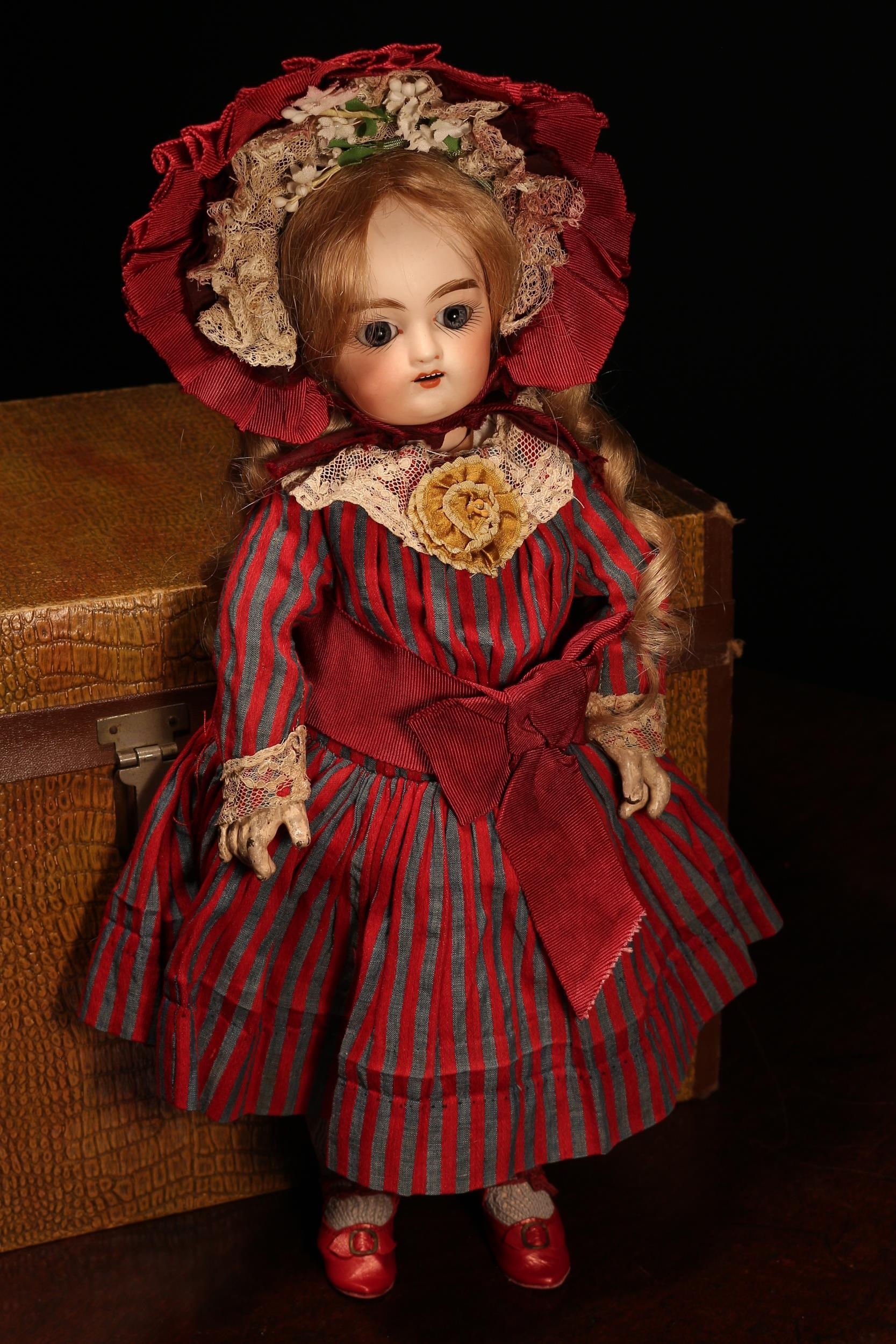 A Pintel & Godchaux (France) bisque head Bébé doll, the bisque head with inset fixed blue glass eyes, painted features including feathered brown eyebrows and fine eyelashes, open mouth revealing upper teeth, blonde wig on cork pate, impressed marks 'C, P7G, D, 7', 38cm high; together with a rectangular shaped travel trunk, the interior fitted with a single lift out tray with various doll clothing and  accessories (quantity)