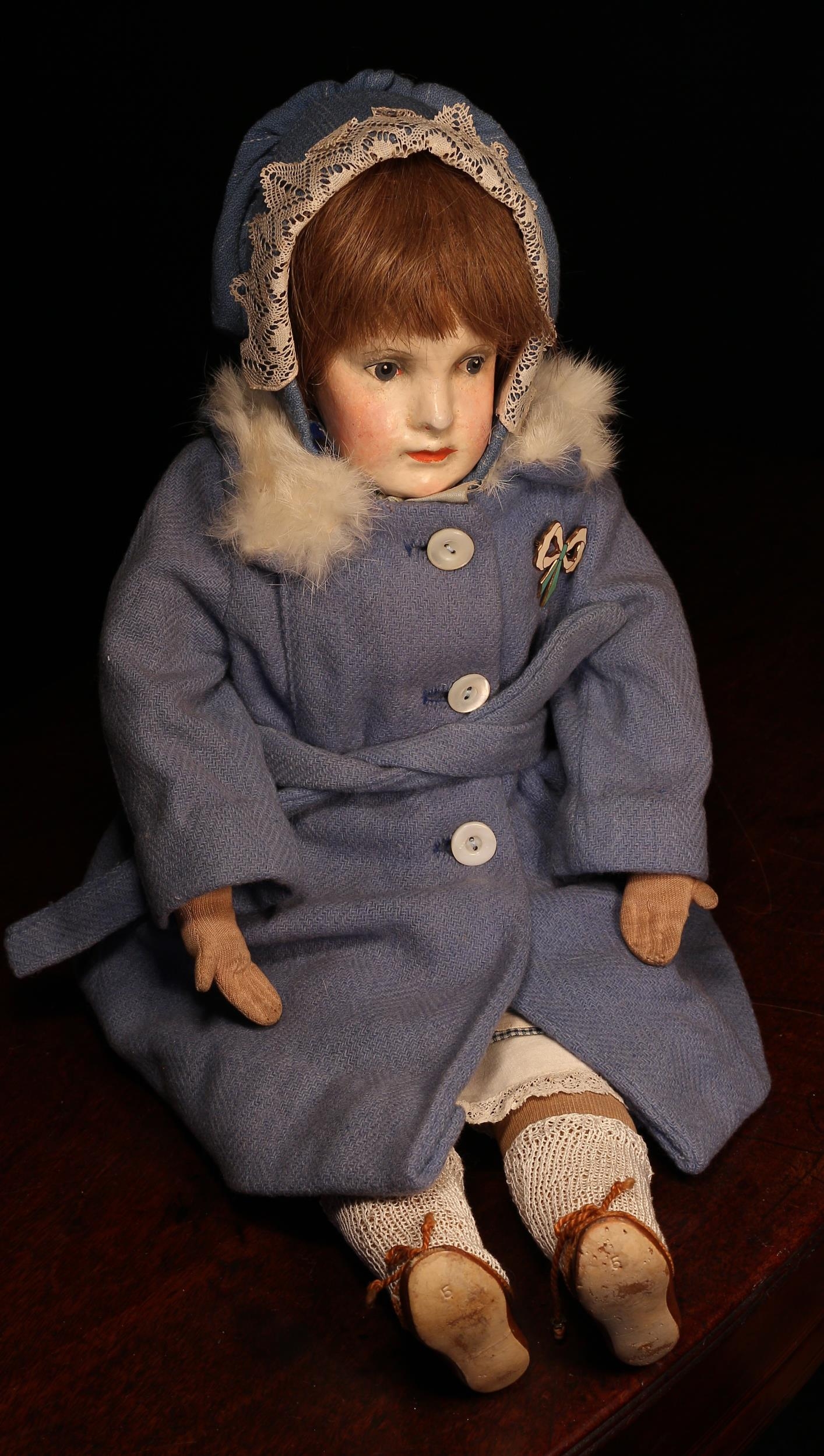 A 1920's Dr Dora Petzold (Germany) painted composition or papier-mâché head and stuffed cloth bodied doll, the painted composition or papier-mâché head with painted features including brown eyebrows, blue eyes, red lips and blush red cheeks, brown wig, stamped 'DORA PETZOLD' mark to lower back, 50.5cm high; together with a woven 'cane' type rectangular shaped sewing basket with cover, the fitted interior with various doll clothing and accessories (quantity)