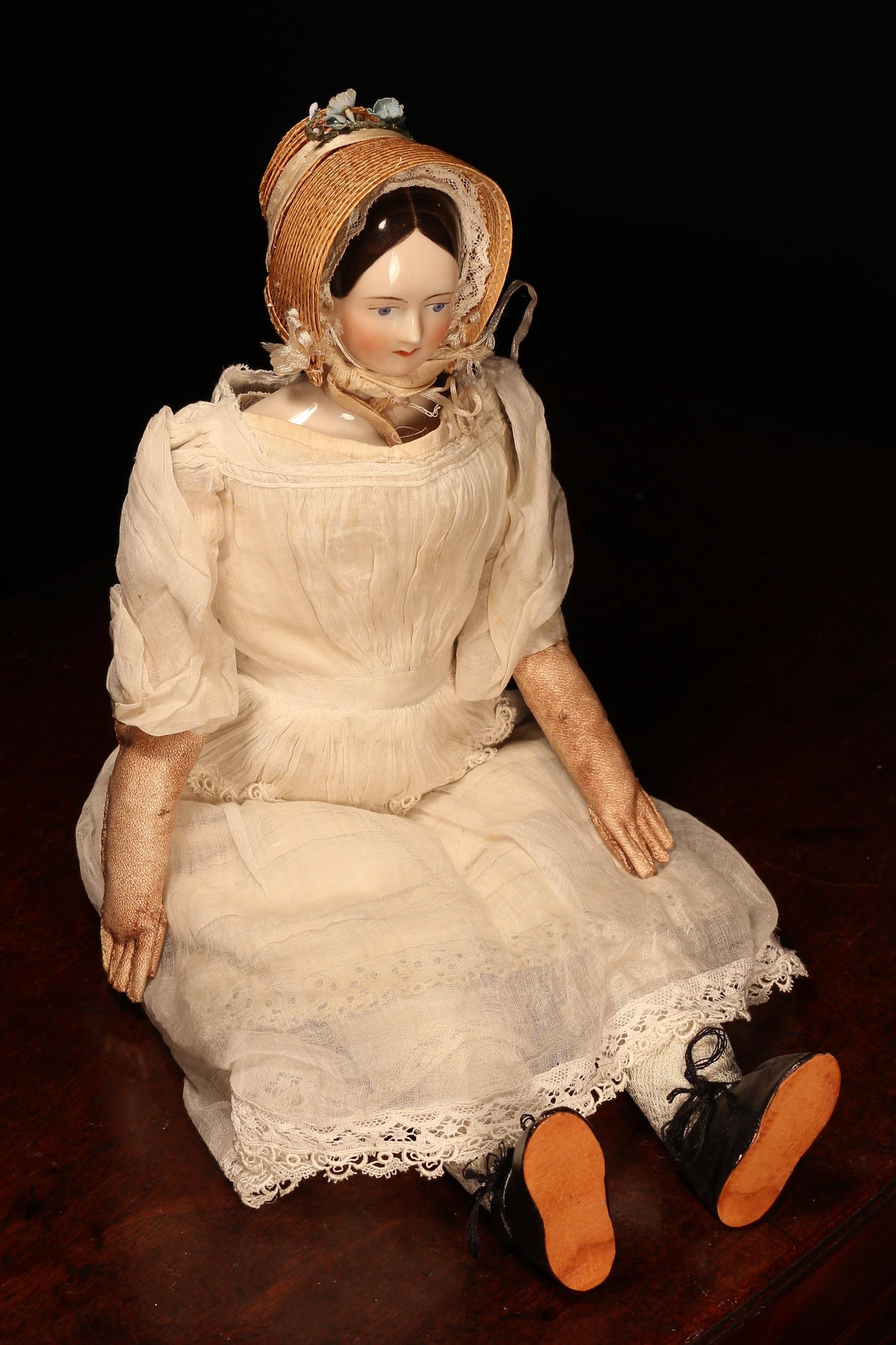 A 19th century glazed china shoulder head doll, the glazed head with painted features including black eyebrows, blue eyes, red lips and black hair, partially stuffed cloth body with kid leather lower arms, 44cm high