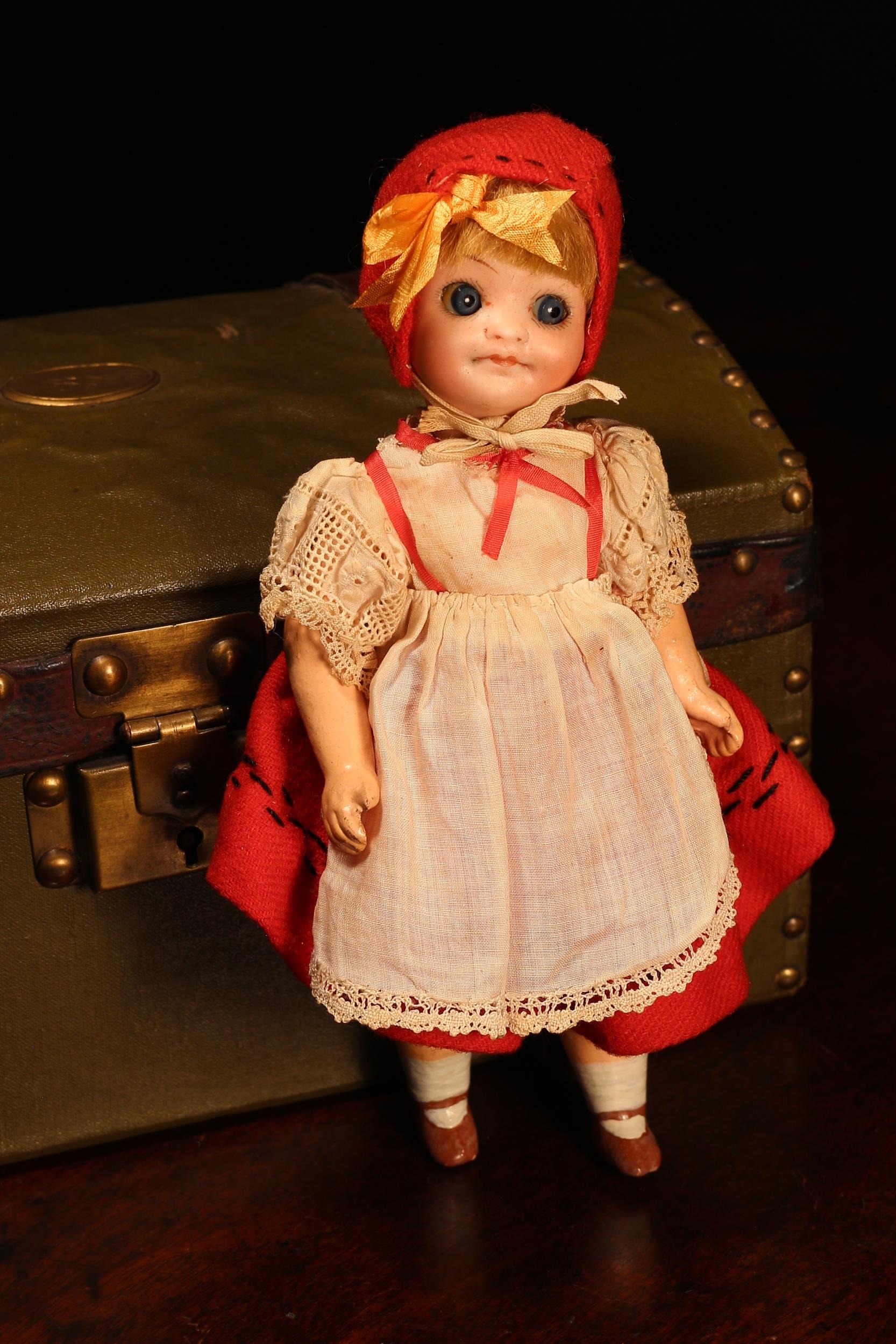 A J.Walther & Sohn (Germany) bisque head novelty Googly-eyed doll, the bisque head with painted features including brown eyebrows, fine eyelashes and red lips, inset fixed side glancing blue glass 'googly eyes', blonde wig on pate, jointed painted composition body, impressed marks '208. 12/0, W&S [INTERTWINED], 12/0, GERMANY', 20.5cm high; together with a green canvas covered rectangular shaped domed top travel trunk, the interior fitted with a single lift out tray with various doll clothing and accessories (quantity)