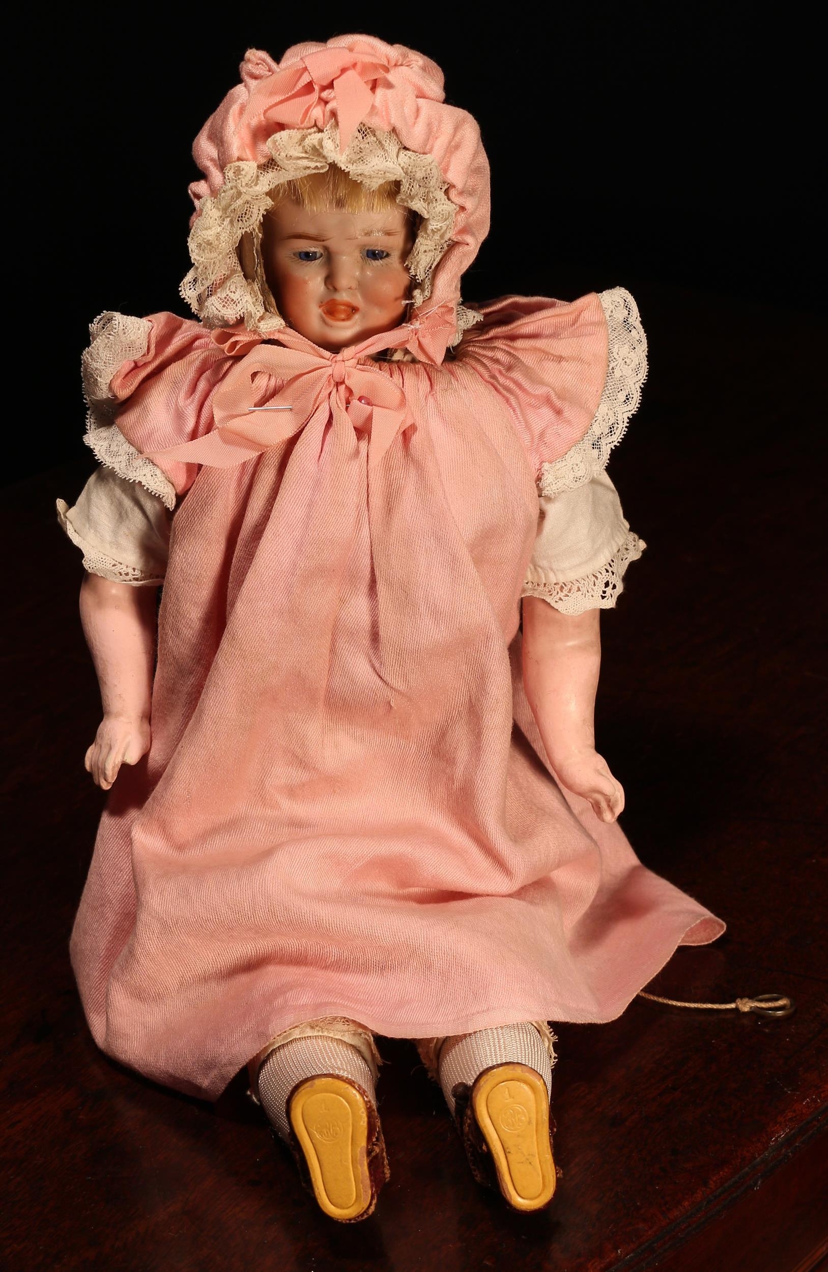 A German multi-faced bisque head doll, attributed to Carl Bergner, the moulded bisque head with swivel mechanism to top which reveals three different faces with various expressions, each with painted features including feathered brown eyebrows and fine eyelashes, two of the faces with fixed inset blue glass eyes, blonde wig, the bisque head encased by a painted composition over cardboard hood, painted composition lower arms and lower legs, impressed marks above the forehead '450, 2/0, DEP', pull chord with 'crying' mechanism to side of torso, 33cm high