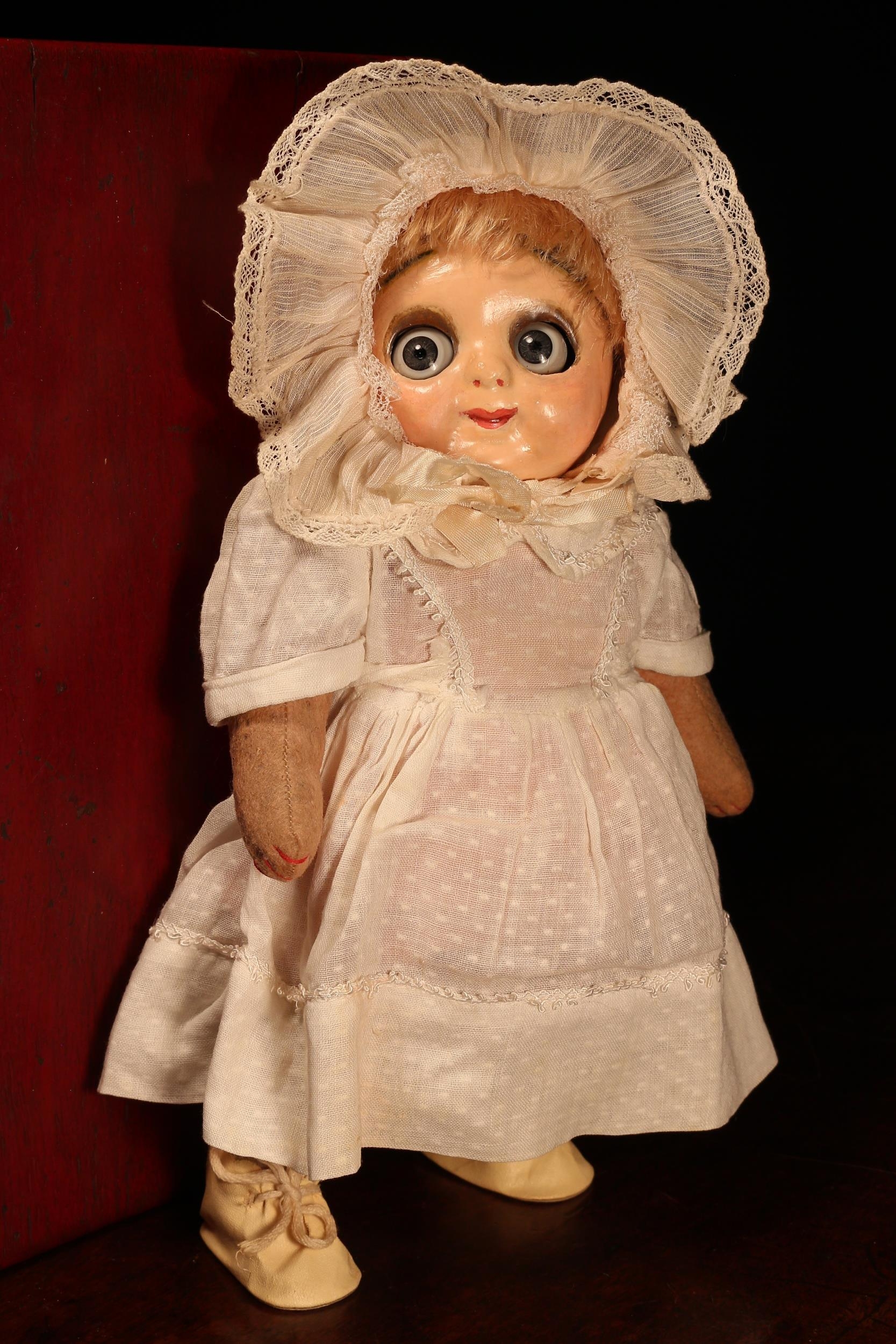 An early 20th century painted composition head and jointed stuffed felt bodied novelty 'Hug Me Kids' Googly eyed doll, the painted composition head with painted features including red lips, inset side glancing blue glass 'googly eyes' with lever to the reverse of the head to operate the eyes, blonde wig, stuffed felt body with inoperable squeaker, 29cm high; together with a rectangular shaped red lacquered box
