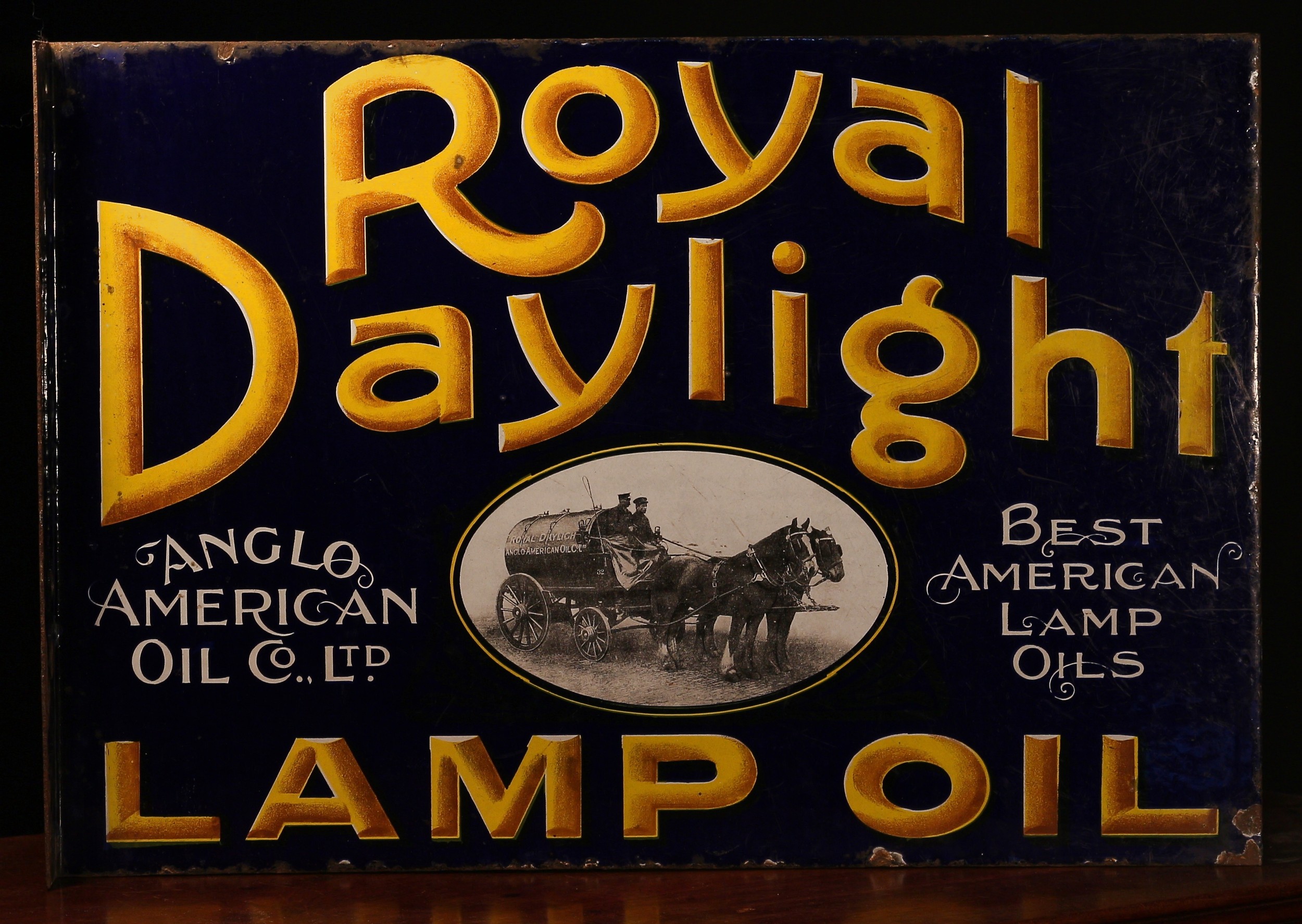 Advertising - a Royal Daylight rectangular shaped flanged double sided pictorial enamel sign, yellow lettering with black drop shadow on a cobalt blue ground, 'ROYAL DAYLIGHT LAMP OIL, ANGLO AMERICAN OIL CO., LTD., BEST AMERICAN OIL LAMPS', the lower section illustrated with an oval shaped pictorial scene depicting a Royal Daylight tank wagon being drawn by a pair of Horses, 'IMPERIAL ENAMEL CO. LTD. BIRM' to lower corner, 37cm high, 53.5cm wide