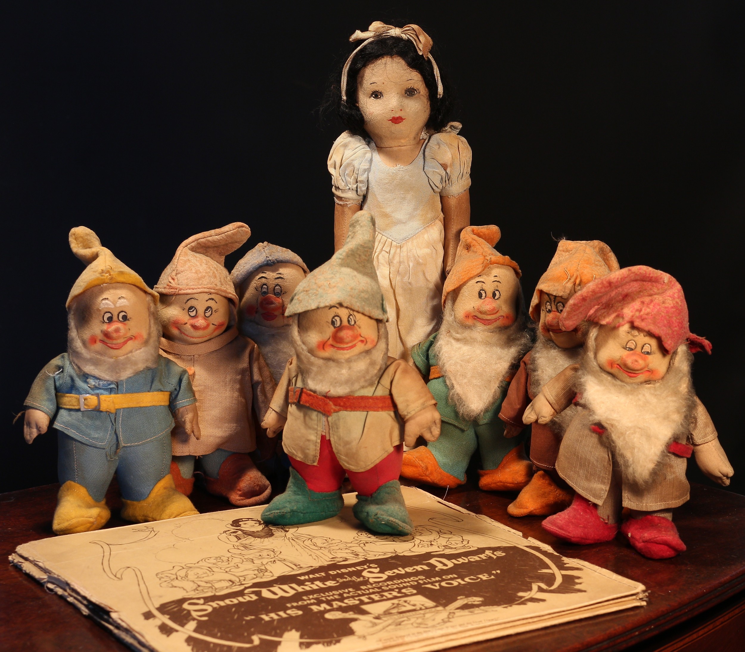 A 1930's set of Chad Valley Snow White and the Seven Dwarfs pressed felt novelty dolls, each with painted features and trademark rectangular 'HYGIENIC TOYS, MADE IN ENGLAND BY CHAD VALLEY CO LTD' labels; a HMV Walt Disney's Snow White and the Seven Dwarfs record (2)