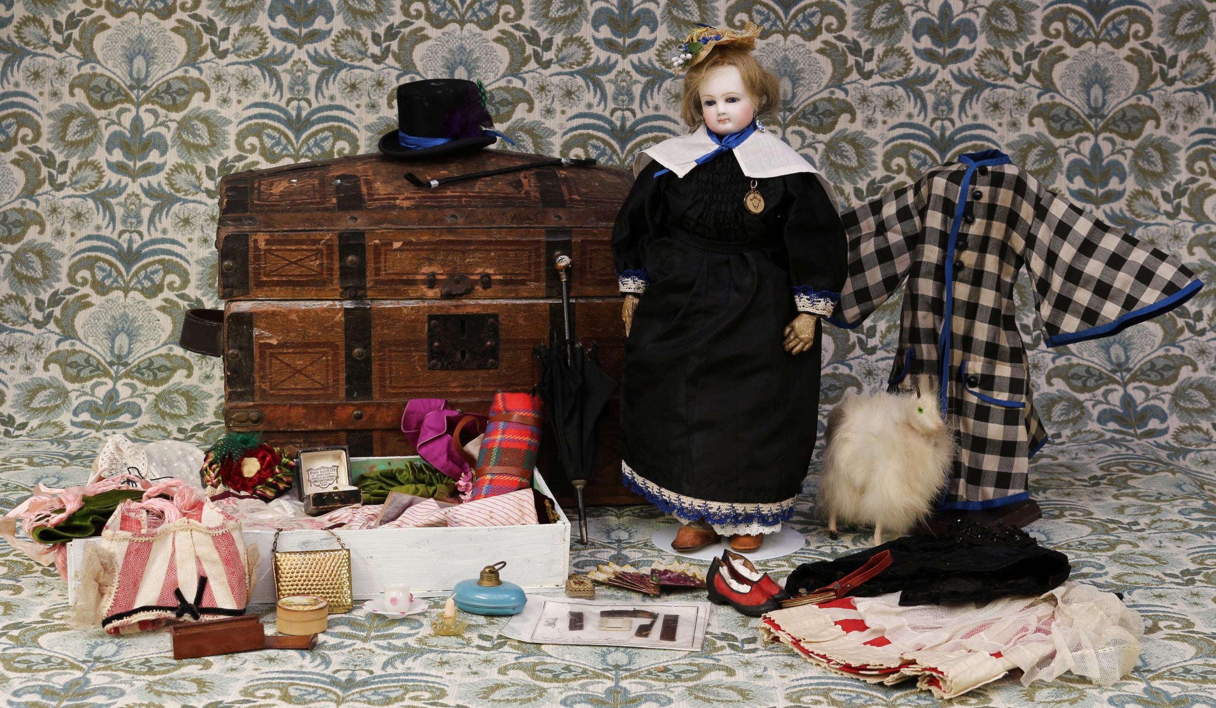 A 19th century pale bisque shoulder and bisque head French Poupée de Mode or fashion doll, the bisque head inset with fixed blue glass eyes and painted features including brown feathered eyebrows, fine eyelashes, red lips and blush cheeks, blonde wig on pate, pierced ears, kid leather body, unmarked head, 36cm high, probably by Bru Jne & Cie (France) or Madame Marie Antoinette Leontine Rohmer or similar; together with a rectangular shaped paper covered domed top trunk, of small proportions, 25cm high, 35.5cm wide, 23cm deep, the interior partially fitted with a lift out tray and inner compartmented sections containing various doll clothing, accessories, miniatures and novelties (quantity)