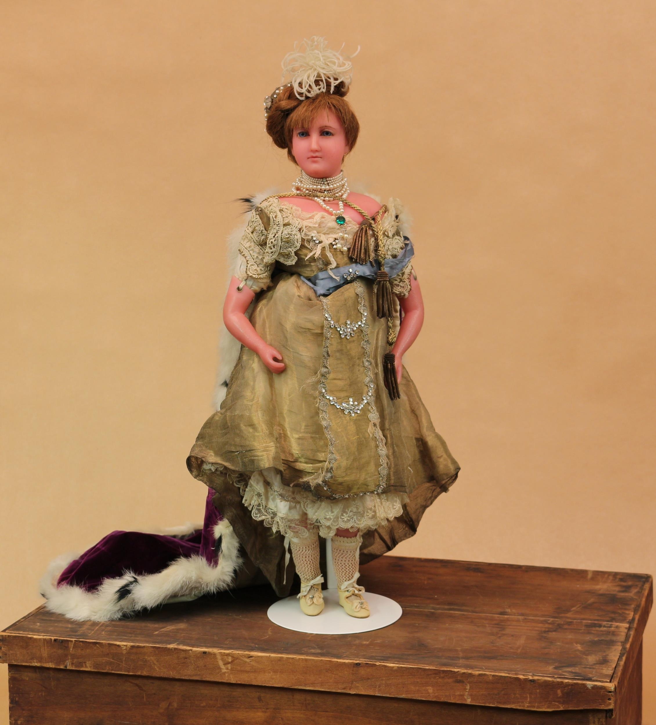 A late 19th century poured wax shoulder head portrait doll of Princess Mary of Teck, attributed to Pierotti, the slightly turned poured wax shoulder head inset with fixed blue glass eyes, inserted eyebrows, brown inserted hair, partially stuffed cloth body with wax limbs attached by brass eyelets, the torso stamped with 'HAMLEY'S, REGENT ST W. DOLLS REPAIRED' mark, 52cm high, together with a rectangular wooden box with lid